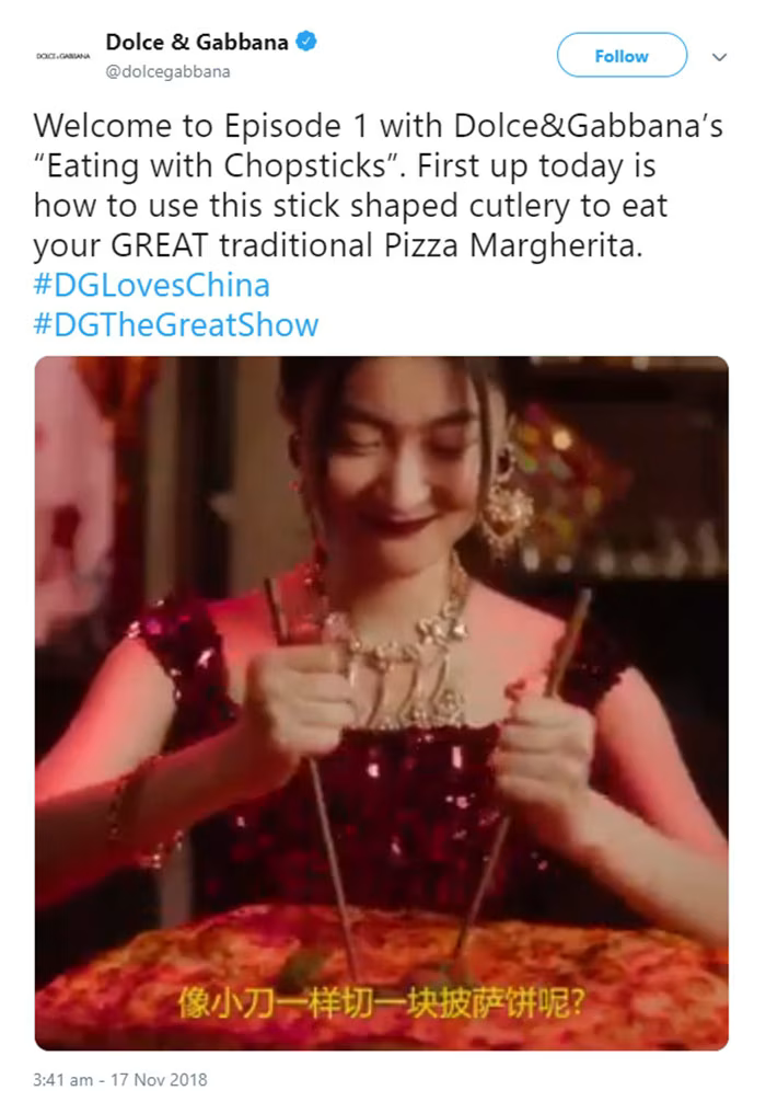 A promotional image from the 2018 "DG Loves China" campaign showing a Chinese model attempting to eat a large Pizza Margherita with chopsticks.