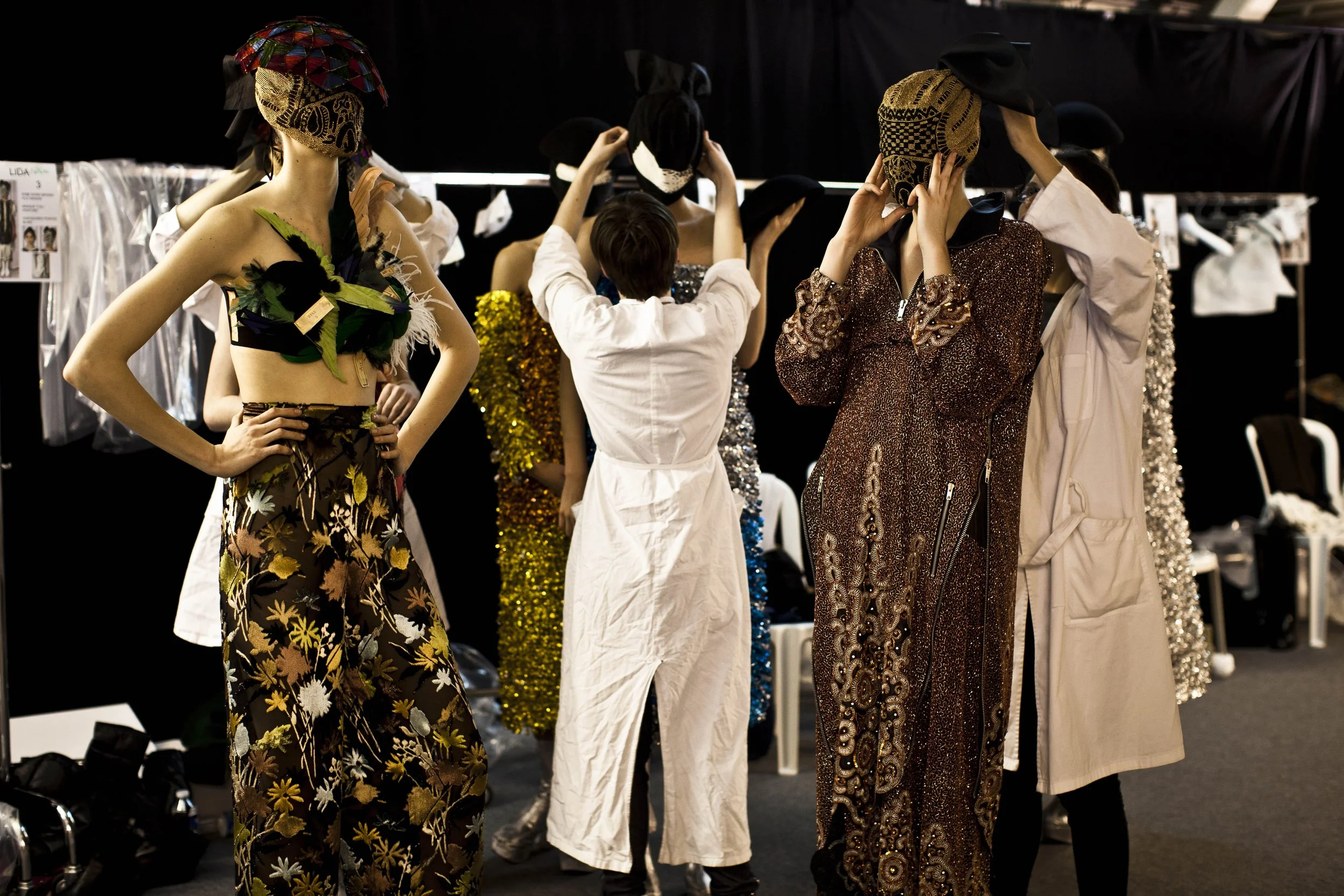 A backstage archival photograph from the Spring 2013 Artisanal show featuring a heavily embellished mask that completely obscures the model's face, embodying the house's code of anonymity.