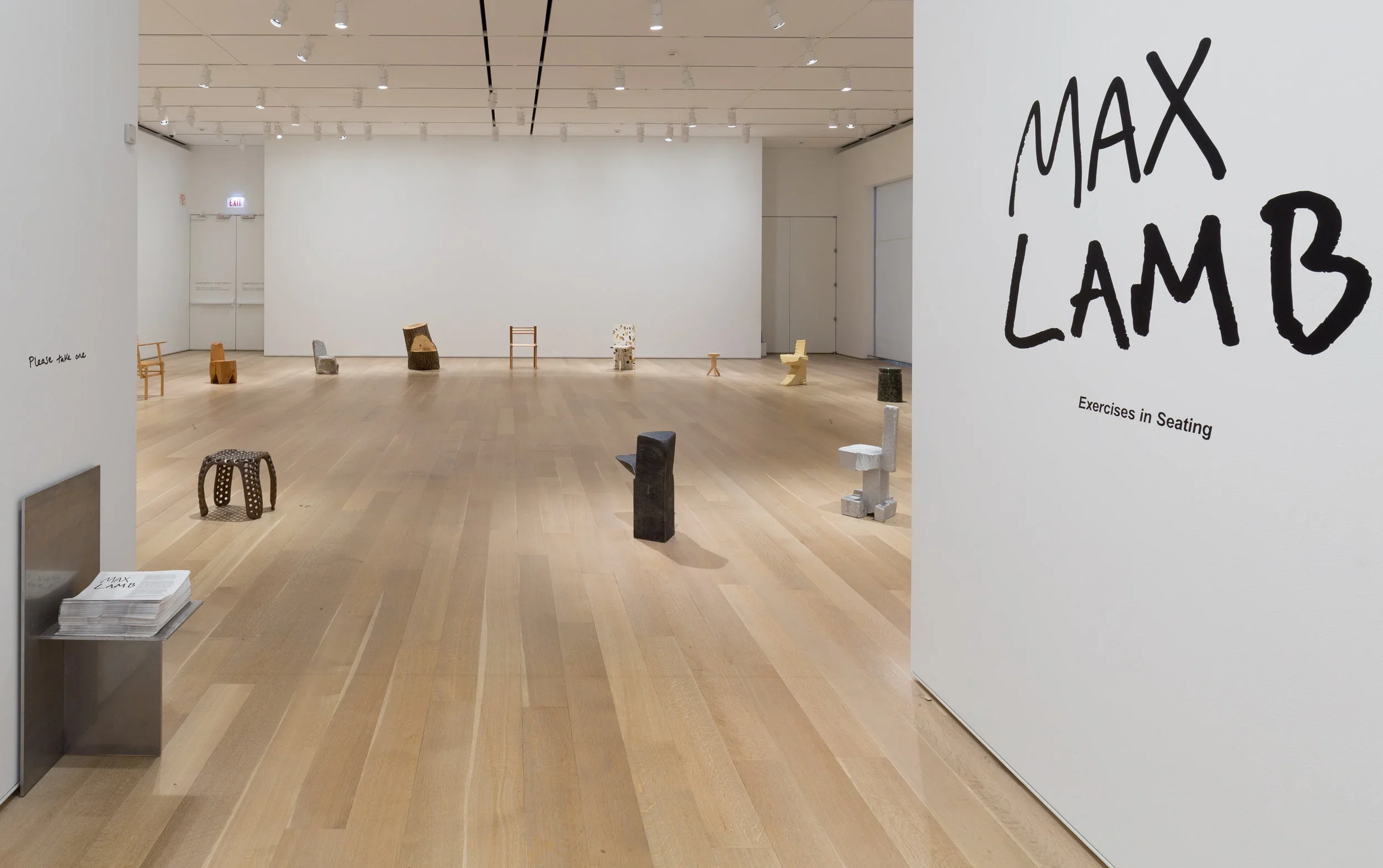A wide gallery view of the "Max Lamb: Exercises in Seating" exhibition at the Art Institute of Chicago, showing diverse hand-crafted chairs widely spaced across a light wood floor with a large hand-painted title wall on the right.