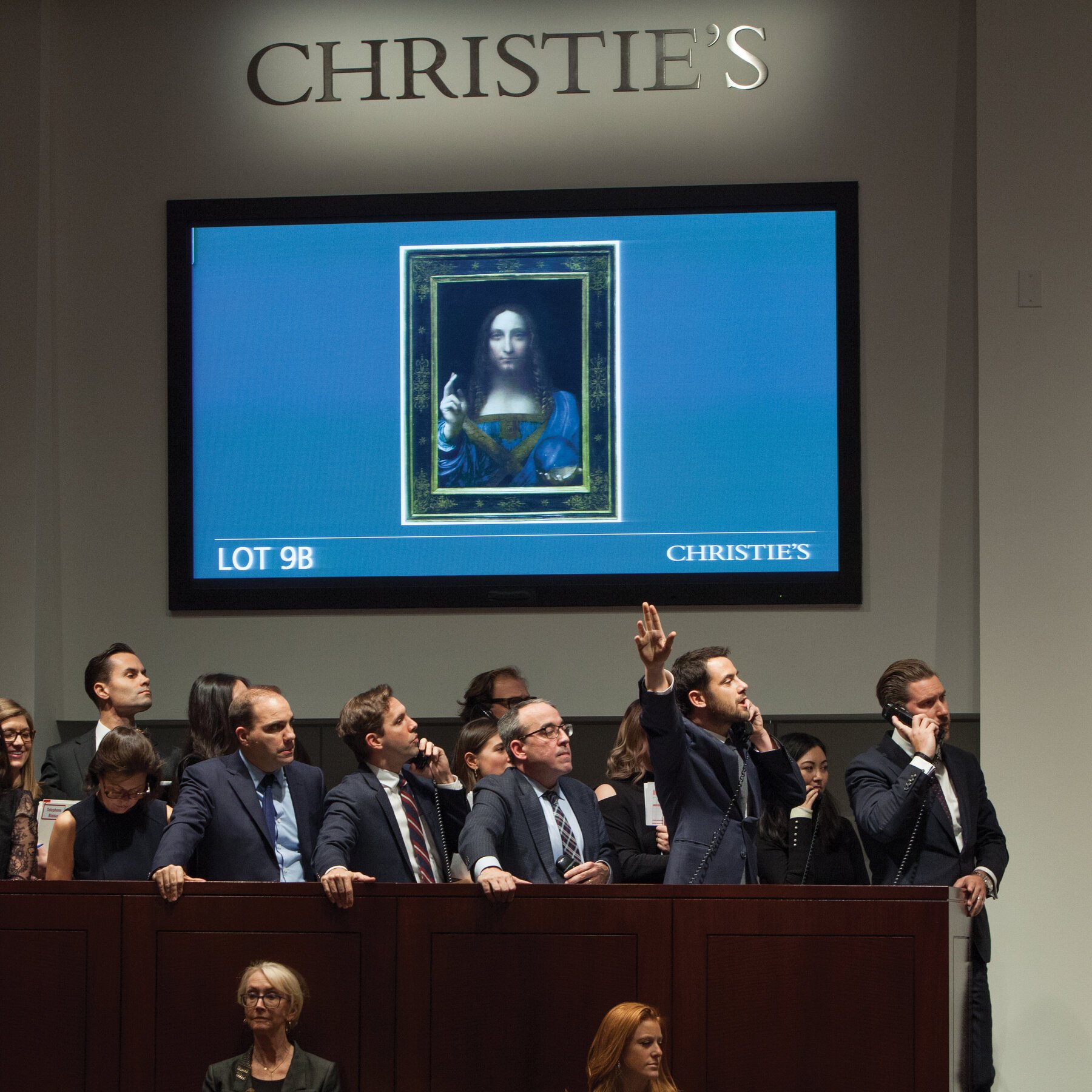A crowded Christie's auction room during the sale of Leonardo da Vinci's Salvator Mundi, representing the public theater of the traditional art market.