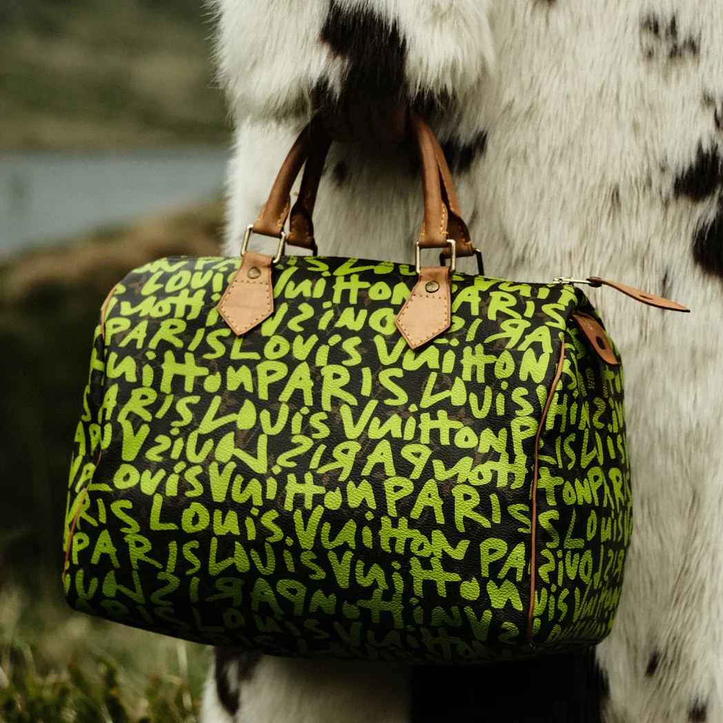 A close-up of the Louis Vuitton neon green Stephen Sprouse graffiti monogram bag, illustrating the artification process where street art is absorbed into luxury branding.