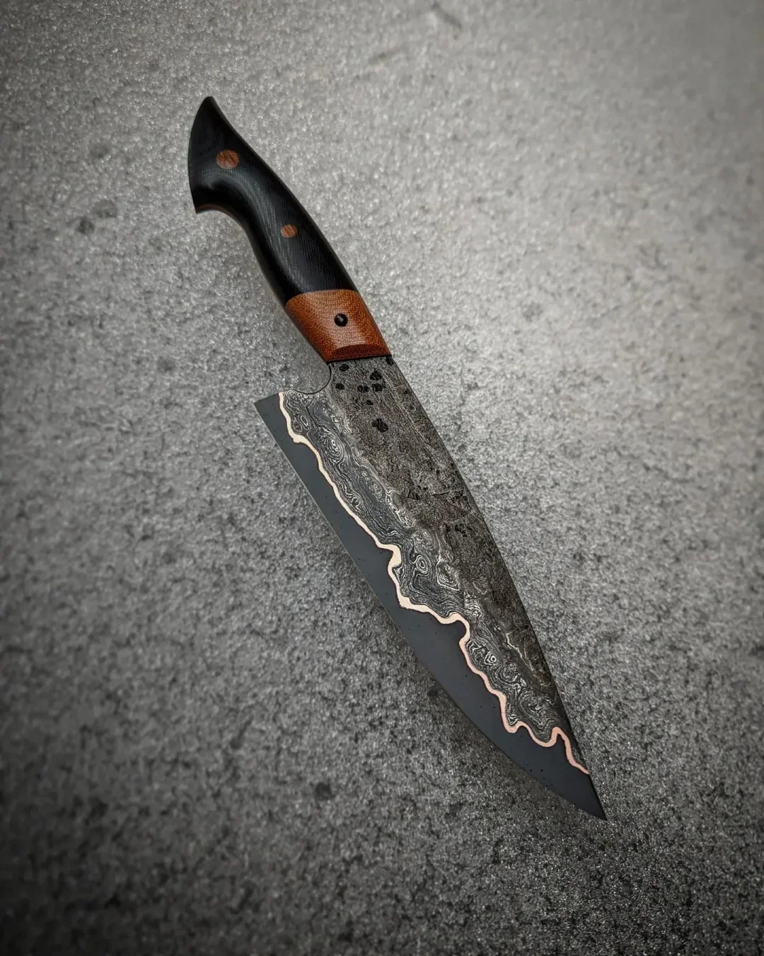 A hand-forged, high-performance chef's knife, representing the 'Generational Knife' case study, featuring a patterned steel blade and a custom wood handle.