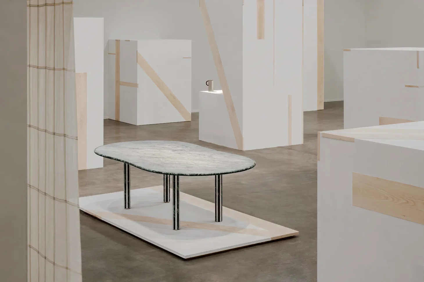 The Stadium d'Hermès marble table by Barber and Osgerby centered on a low platform amidst tall plaster and beechwood geometric volumes at La Pelota.