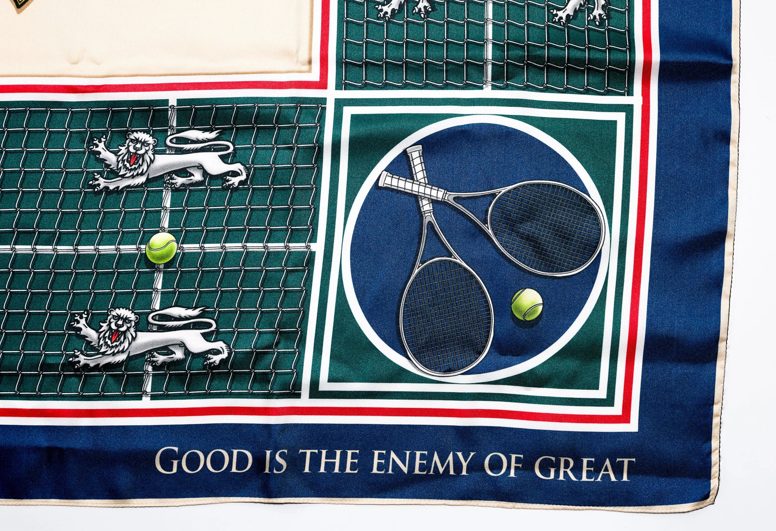 A forensic macro photograph of the Court of Tenacity silk scarf, focusing on the sharp typography of the motto "GOOD IS THE ENEMY OF GREAT" and the intricate linework of the tennis racket and net motifs.