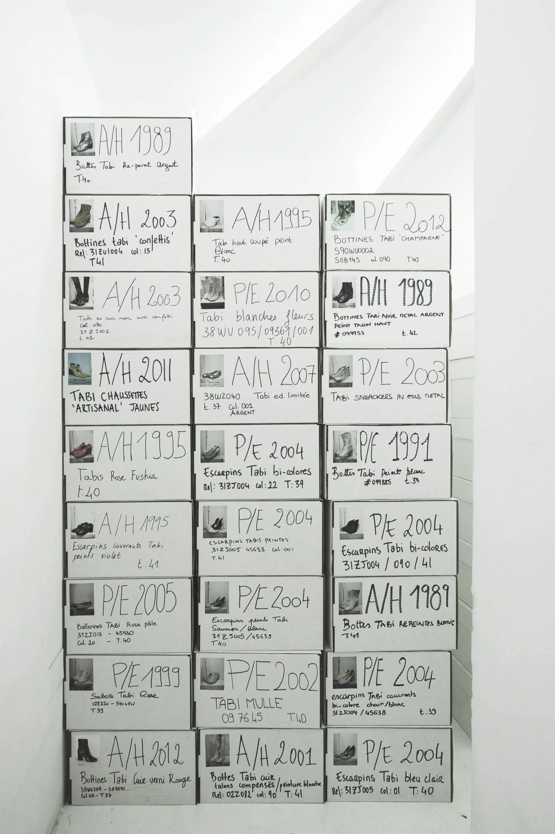 A perspective shot of the Maison Margiela archival storage shelves, containing multiple iterations of the Tabi shoe, documenting its evolution and community-led cultural sovereignty.