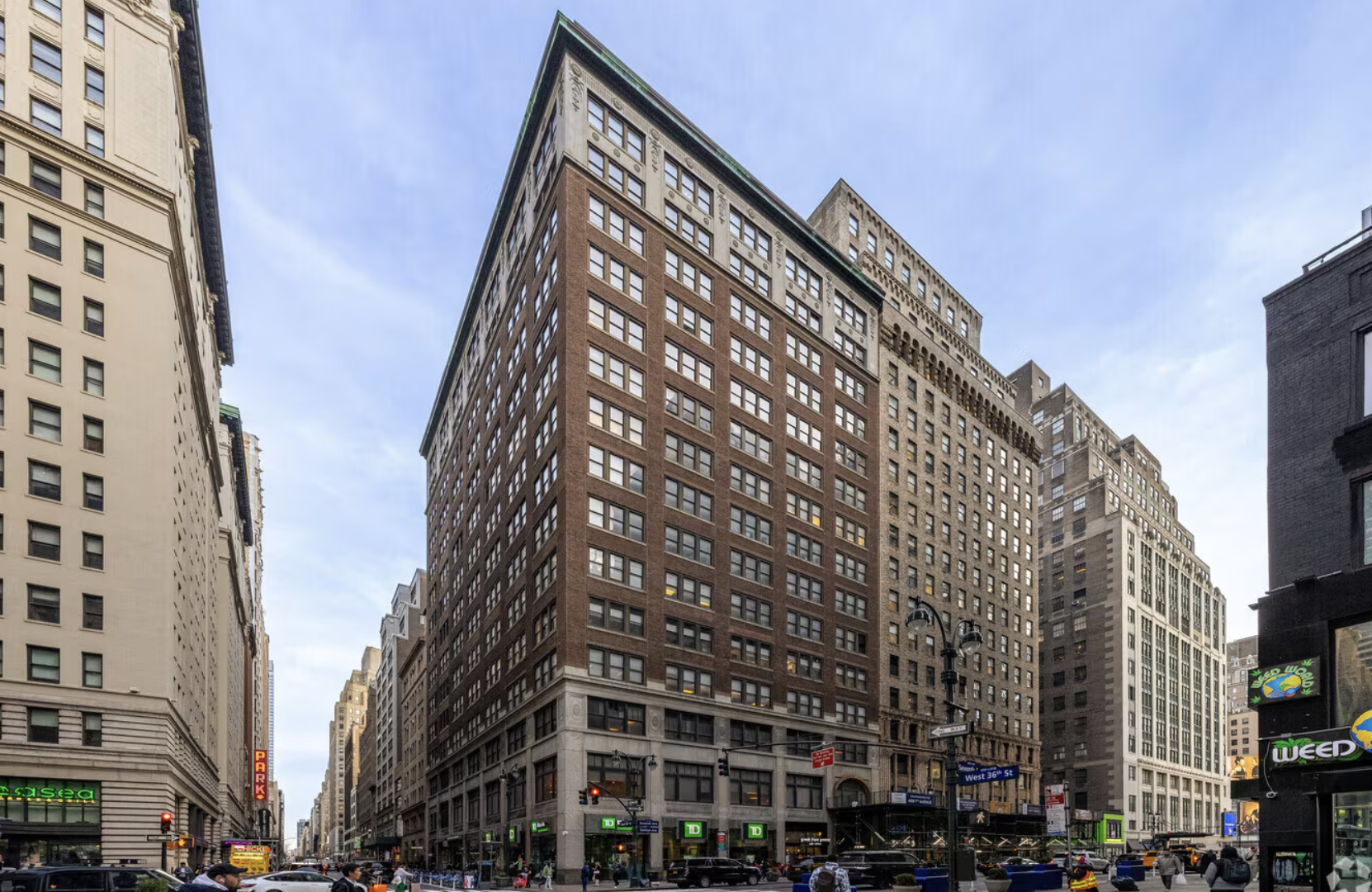 An eye-level exterior view of the historic Armion Building at 469 Fashion Avenue in New York City, showcasing its characteristic 1920s setback architectural silhouette, limestone facade, and large industrial windows on a bright day.