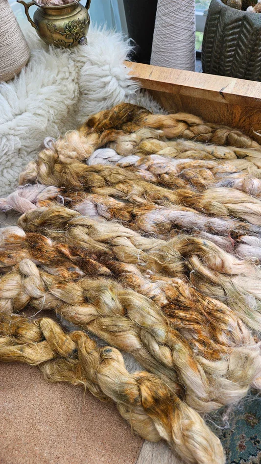 A close-up photograph showcasing multiple thick hanks of raw flax fiber, beautifully braided.