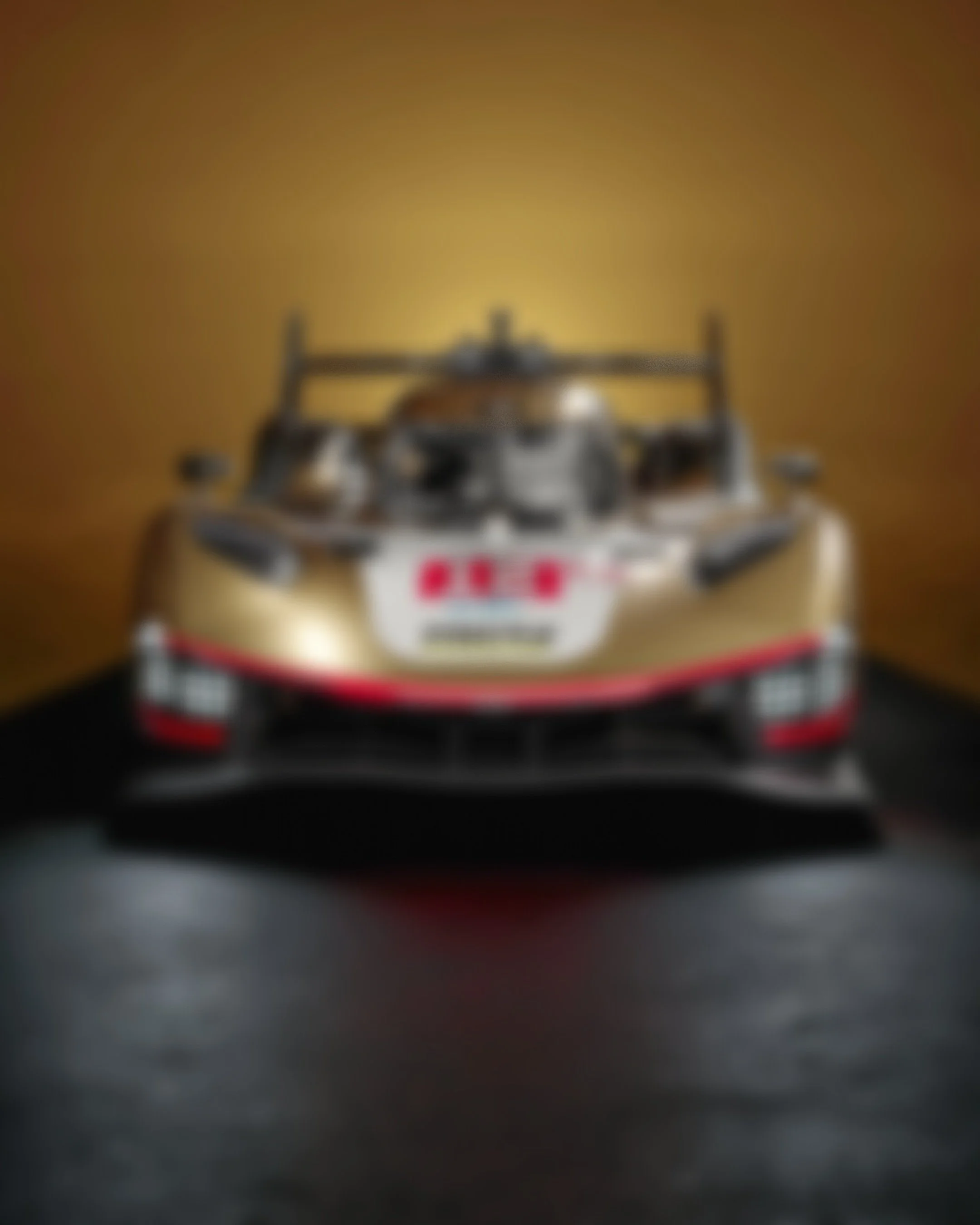 A race car on display against a yellow background, viewed from the front.