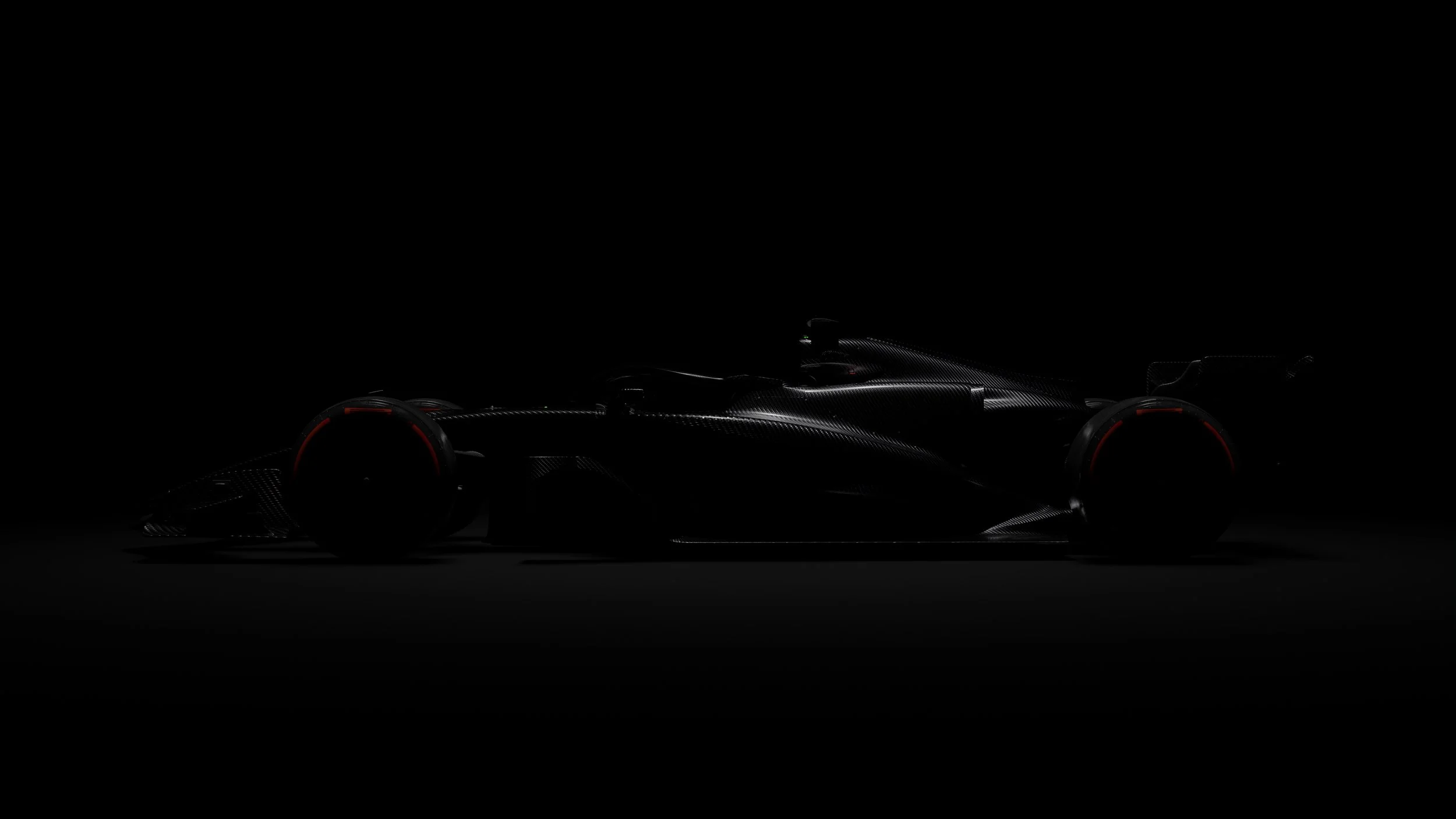 A sleek, black race car with a low profile and modern aerodynamic design, illuminated subtly from below, set against a dark background.