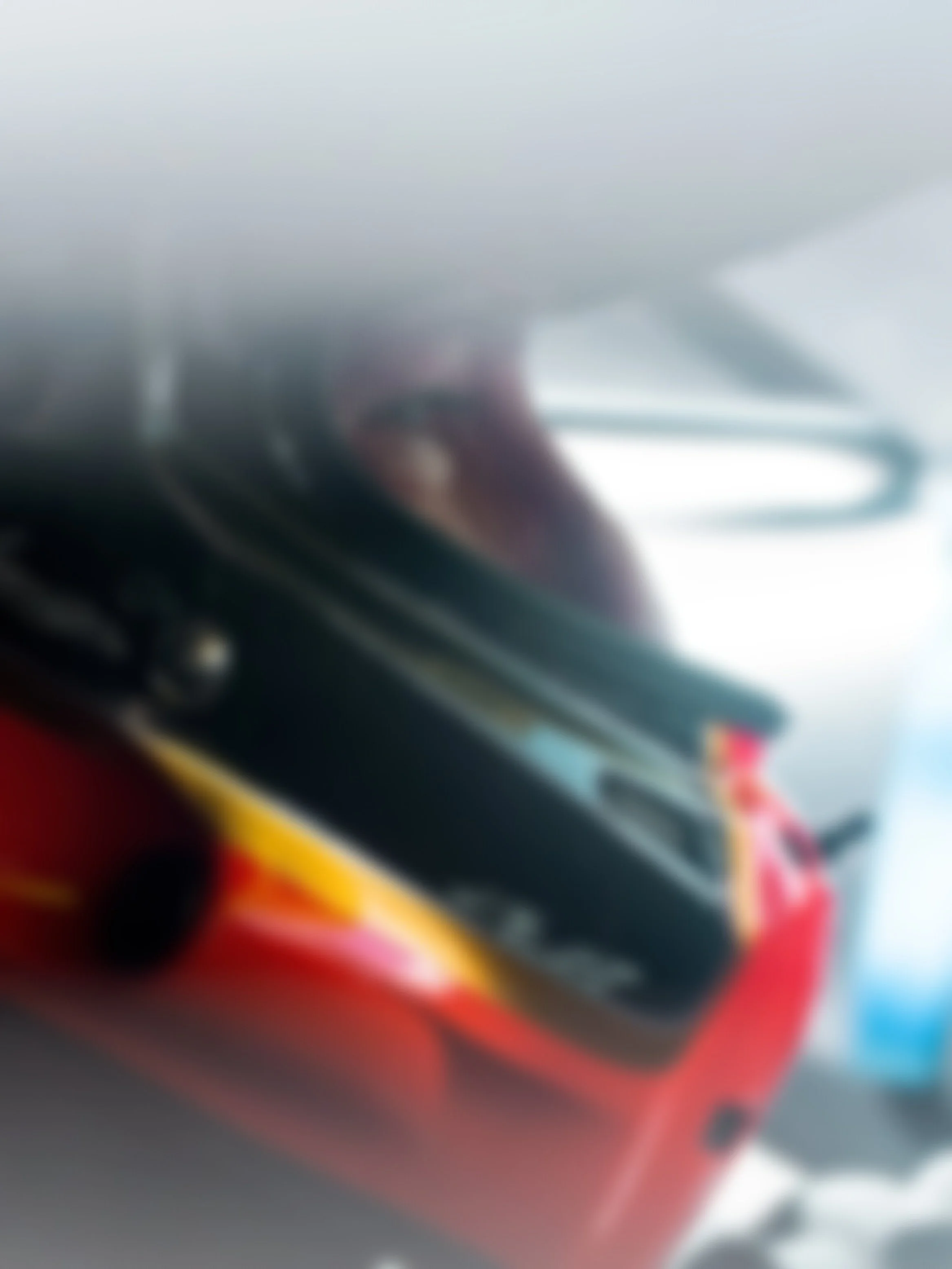 A person wearing a racing helmet with a red, yellow, and black design, sitting in a vehicle.