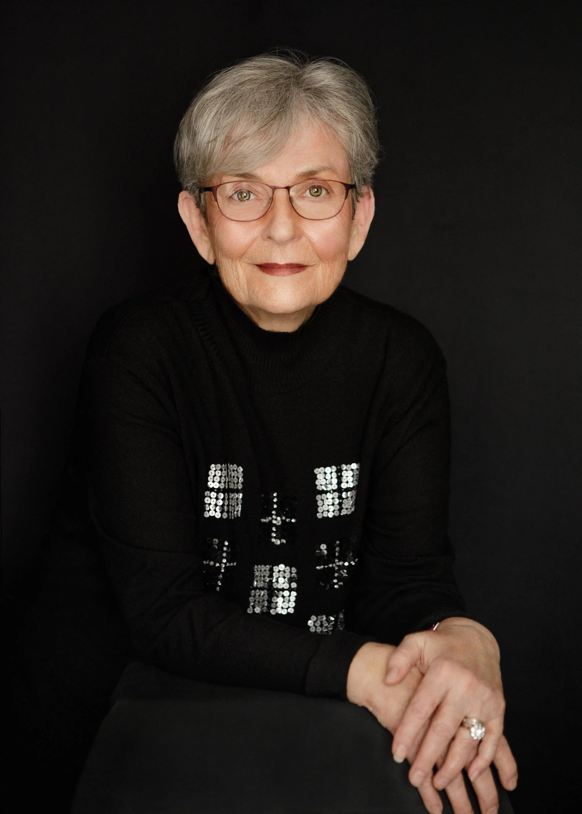 Mature woman wearing a black sweater, gently posing and looking directly to camera at Angelique Portrait Photography studio in Edinburgh.