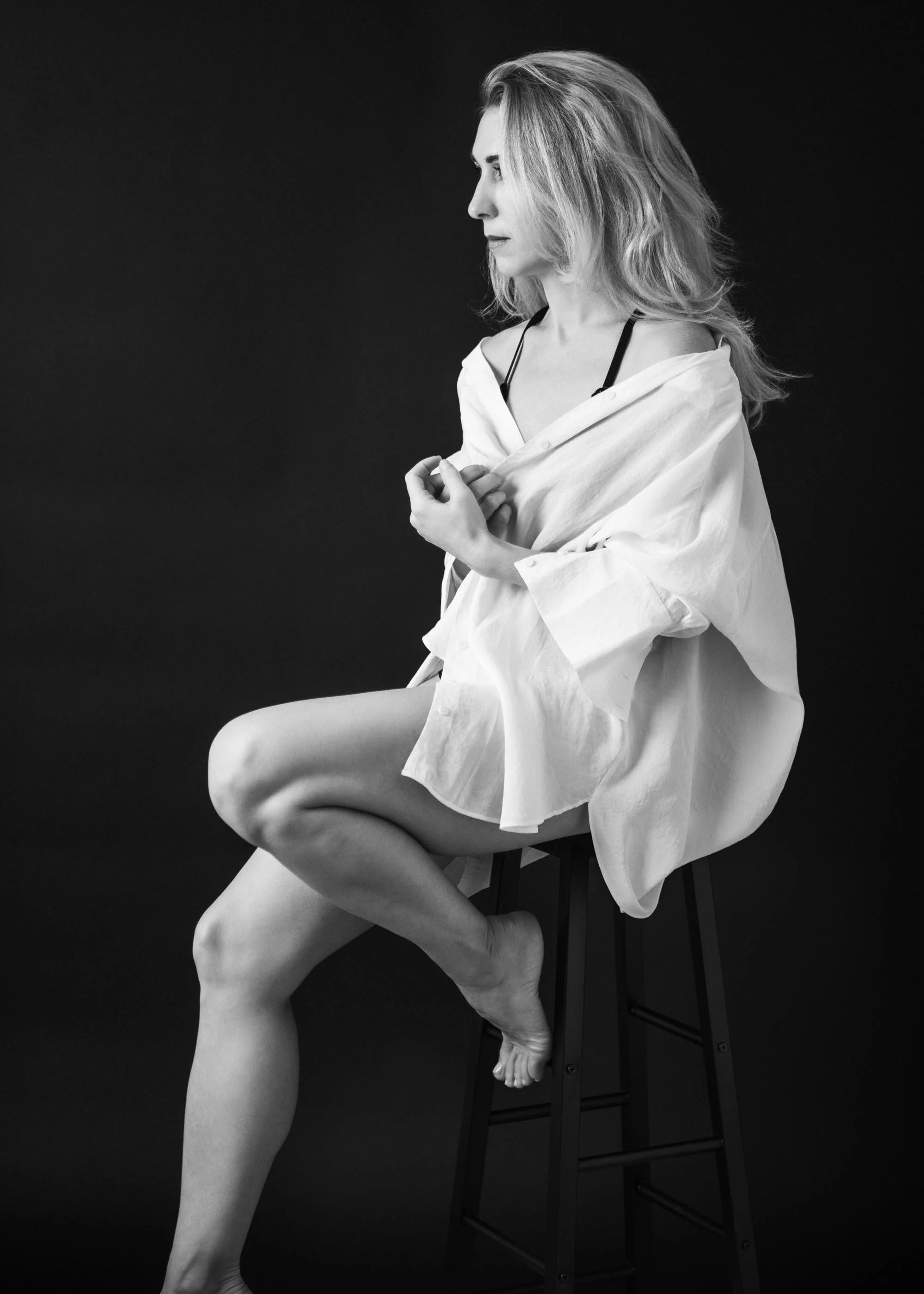 black and white image of a woman wearing a white shirt and facing the light.