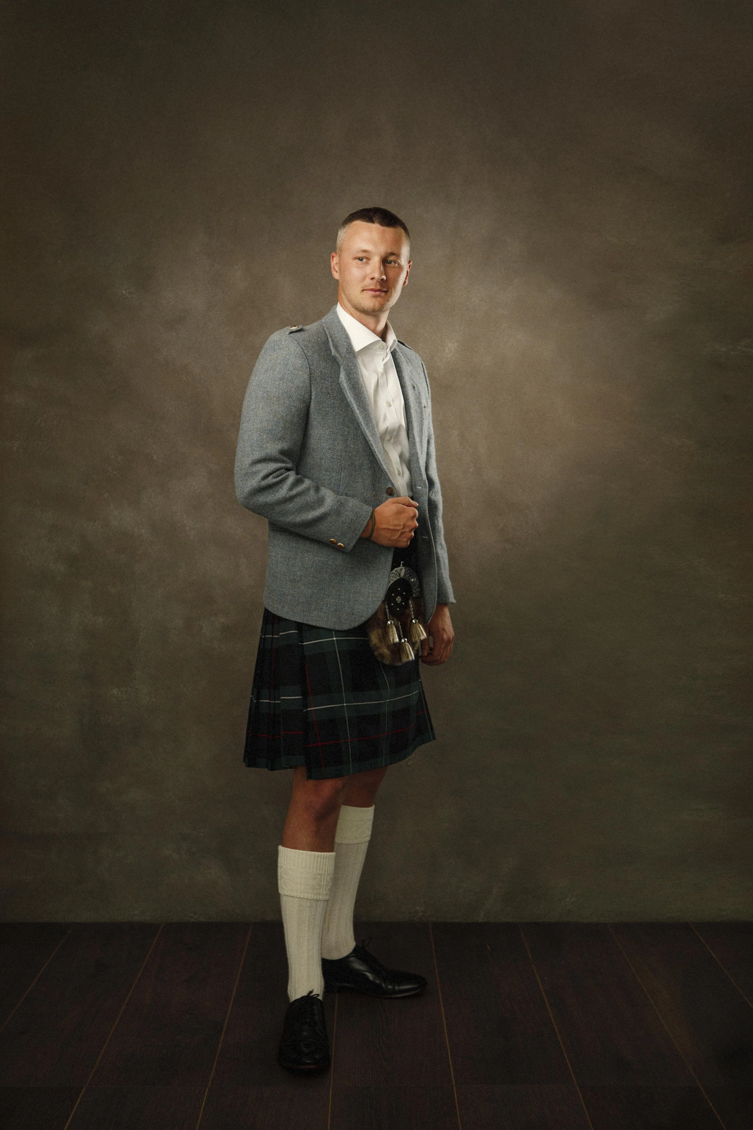 Young man in traditional Scottish kilt, fine art heritage portrait against hand-painted studio backdrop, East Lothian