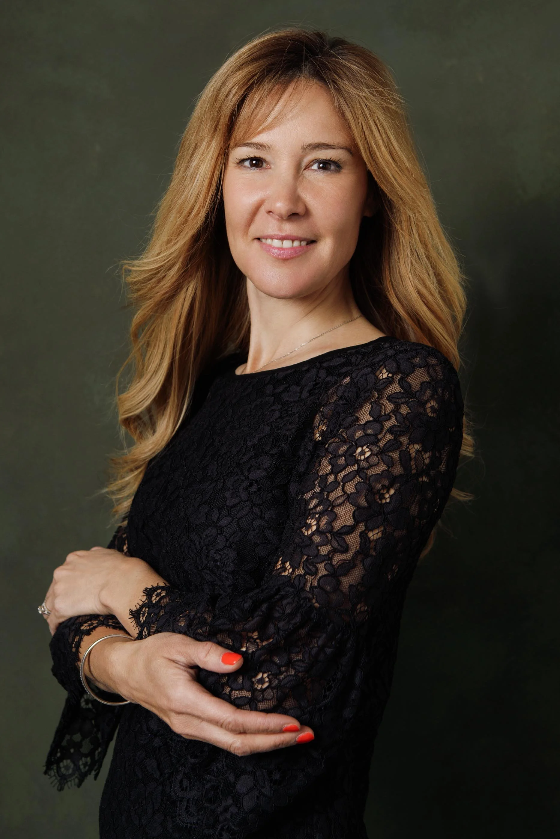 Elegant blond woman wearing black lace dress, looking to the camera and softly smiling