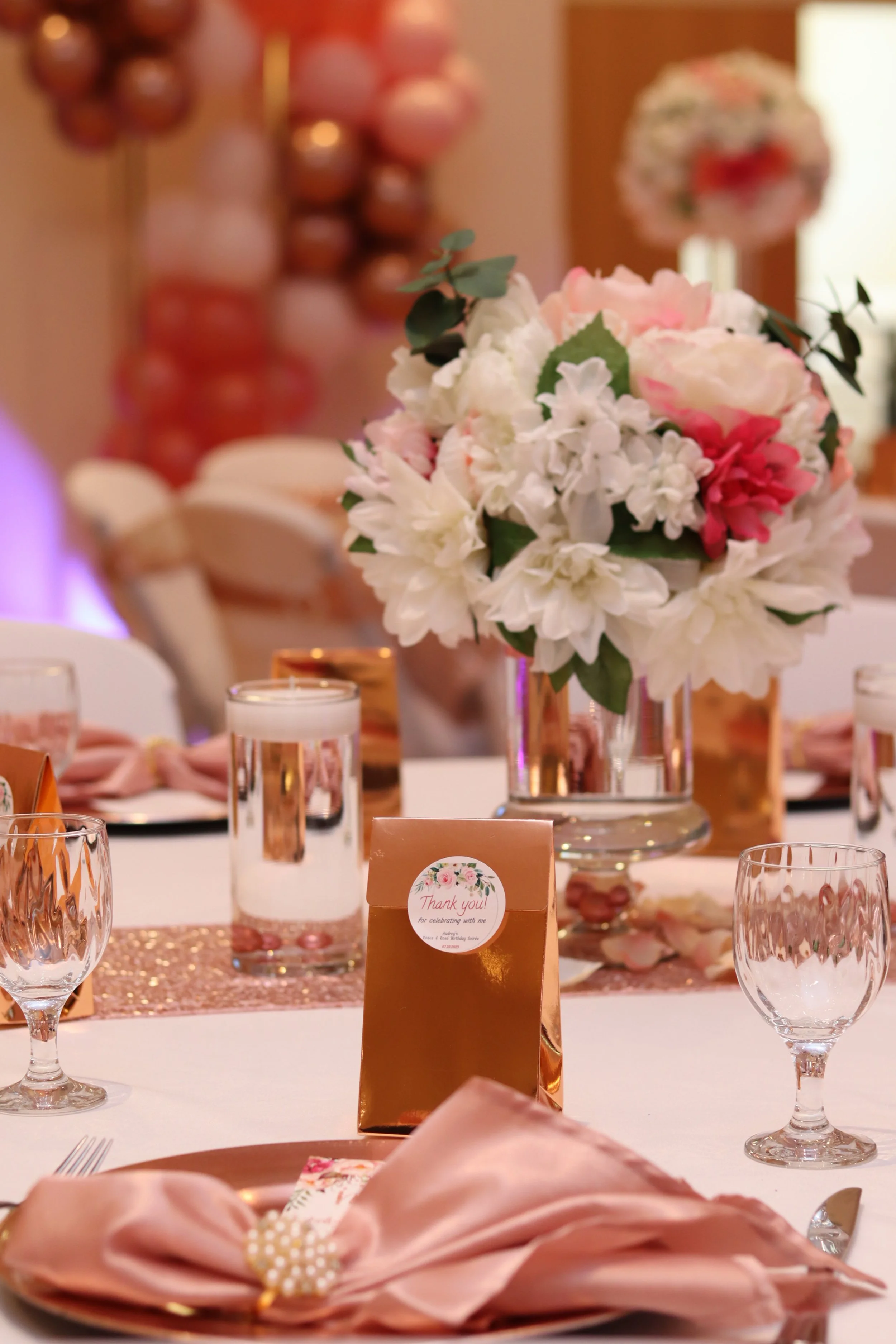 Elegant floral centerpiece with pink and white flowers on a decorated table for a celebration.