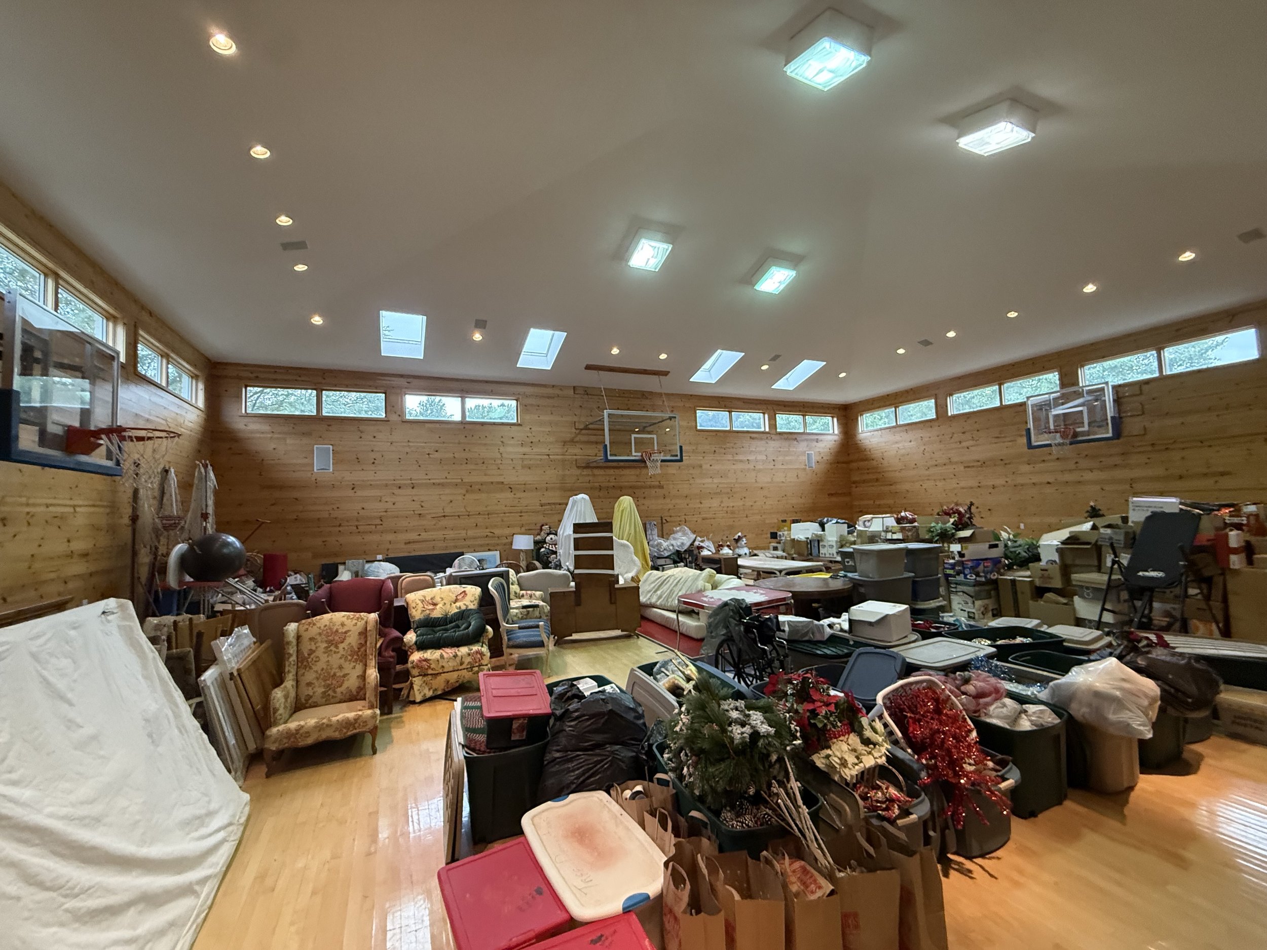 A gymnasium filled with clutter and furniture, including chairs, boxes, and holiday decorations.