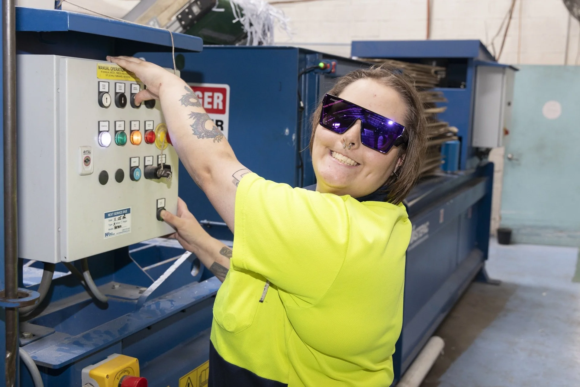A woman wearing safety glasses and a high-visibility yellow shirt operating an industrial control panel as part of our Valley Secure Documents team. 