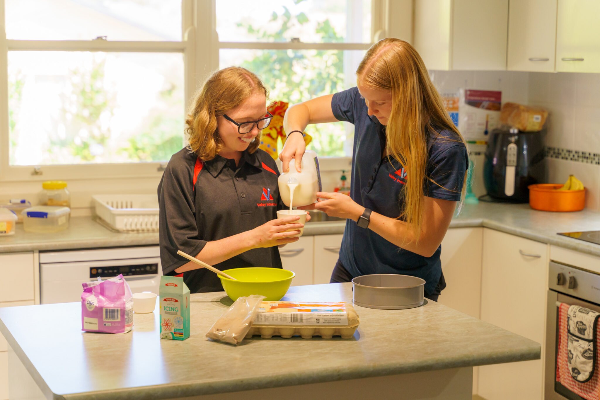 Two women baking in a kitchen, illustrating the benefits of Valley's independence supports. 