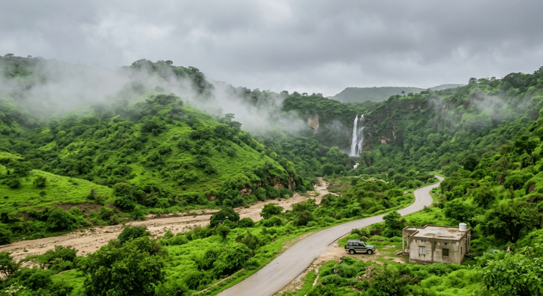 The monsoon mist and green, lush environment, contrasting it with a dry wadi bed and traditional, low-rise buildings..