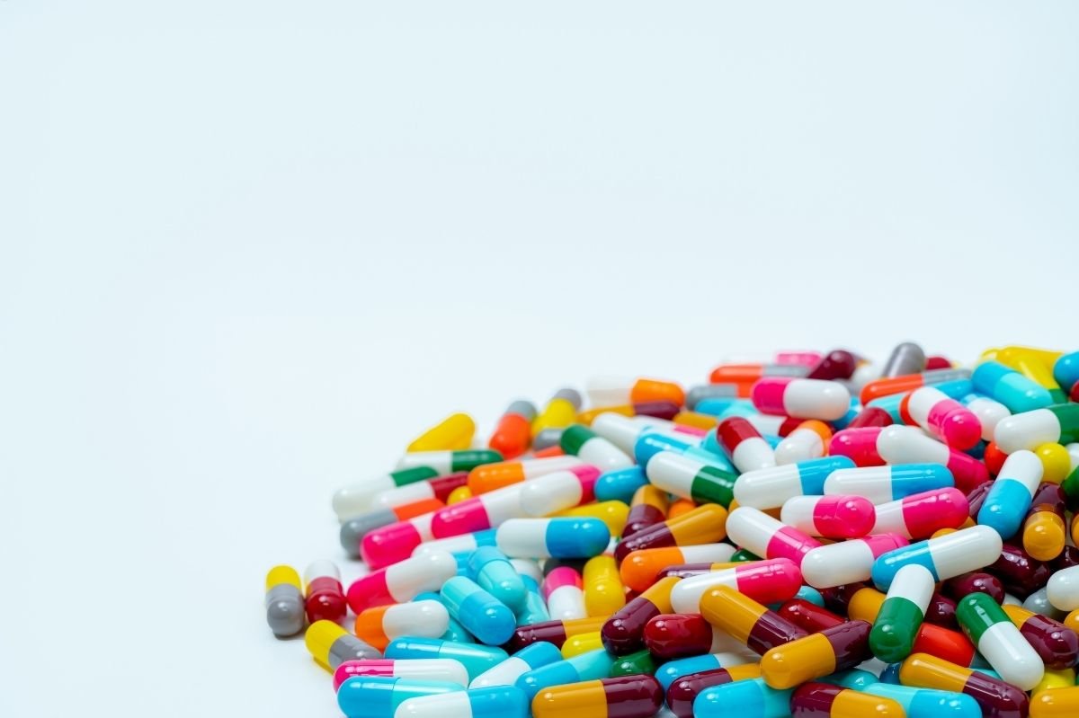 Assorted colorful prescription capsules scattered on a white background, representing medication treatment.
