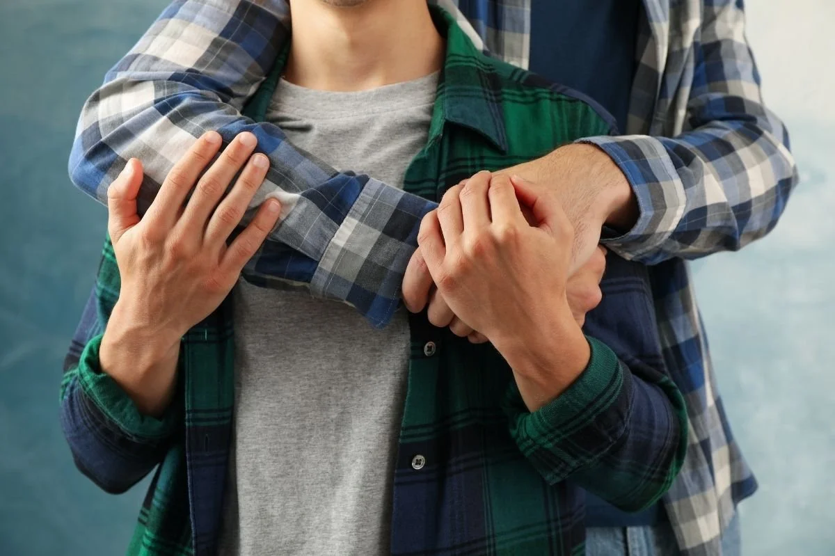 Close up of same sex male couple embracing and holding hands in a supportive, intimate moment.