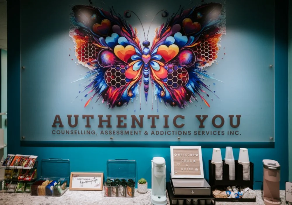 olorful butterfly artwork on a wall above a refreshment station at Authentic You Counselling, featuring snacks, tea, and drink supplies.