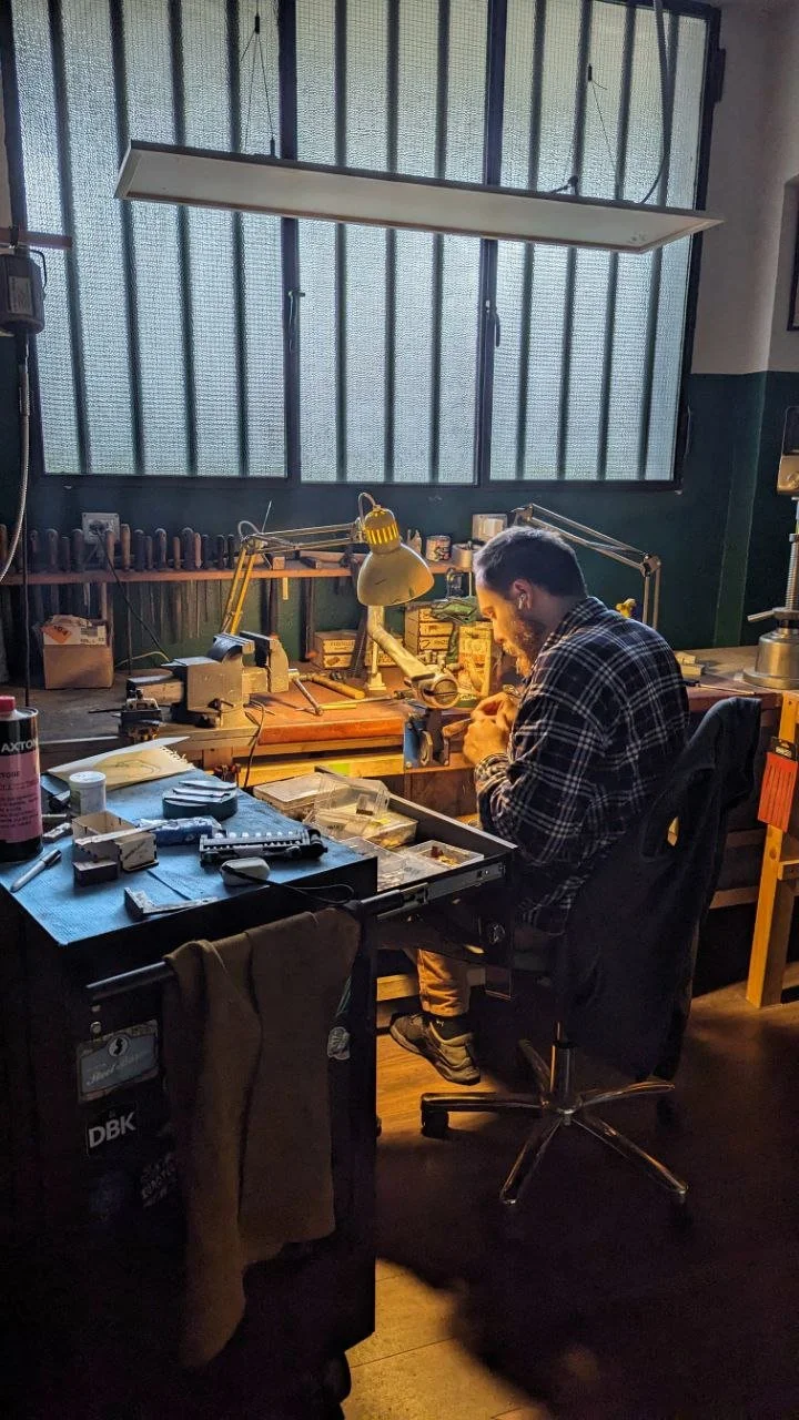 Artigiano coltellinaio che sta lavorando nel suo laboratorio circondato da attrezzatura