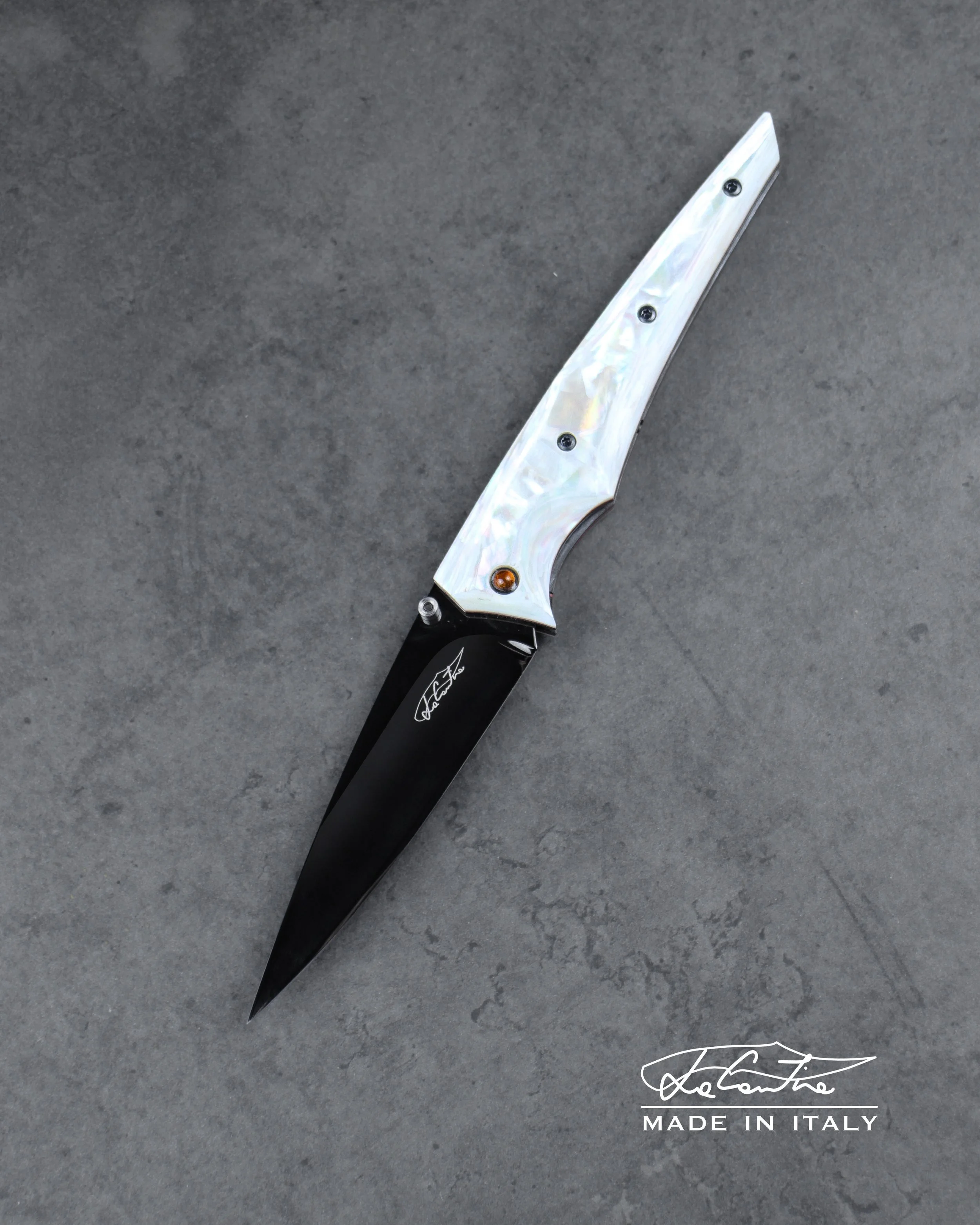 LAMA: RWL34,60HRC, trattamento DLC. MANICO: Madreperla, Gemme di ambra incastonate nel pivot,, G10 rosso, meccanica in acciaio temperato con DLC, distanziale in carbonio