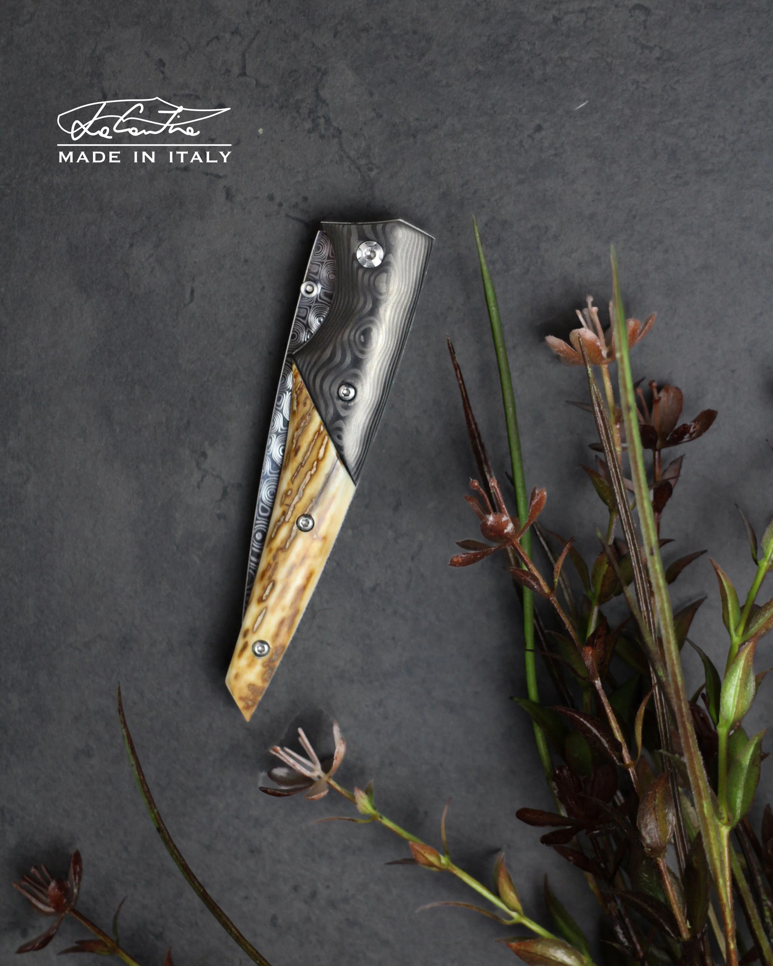 LAMA: Damasteel rose.        
MANICO: Bolster in carbonio uniti by fatcarbon, zanna di mammut fossile, G10 nero, acciaio temperato con meccanica DLC, distanziale in carbonio