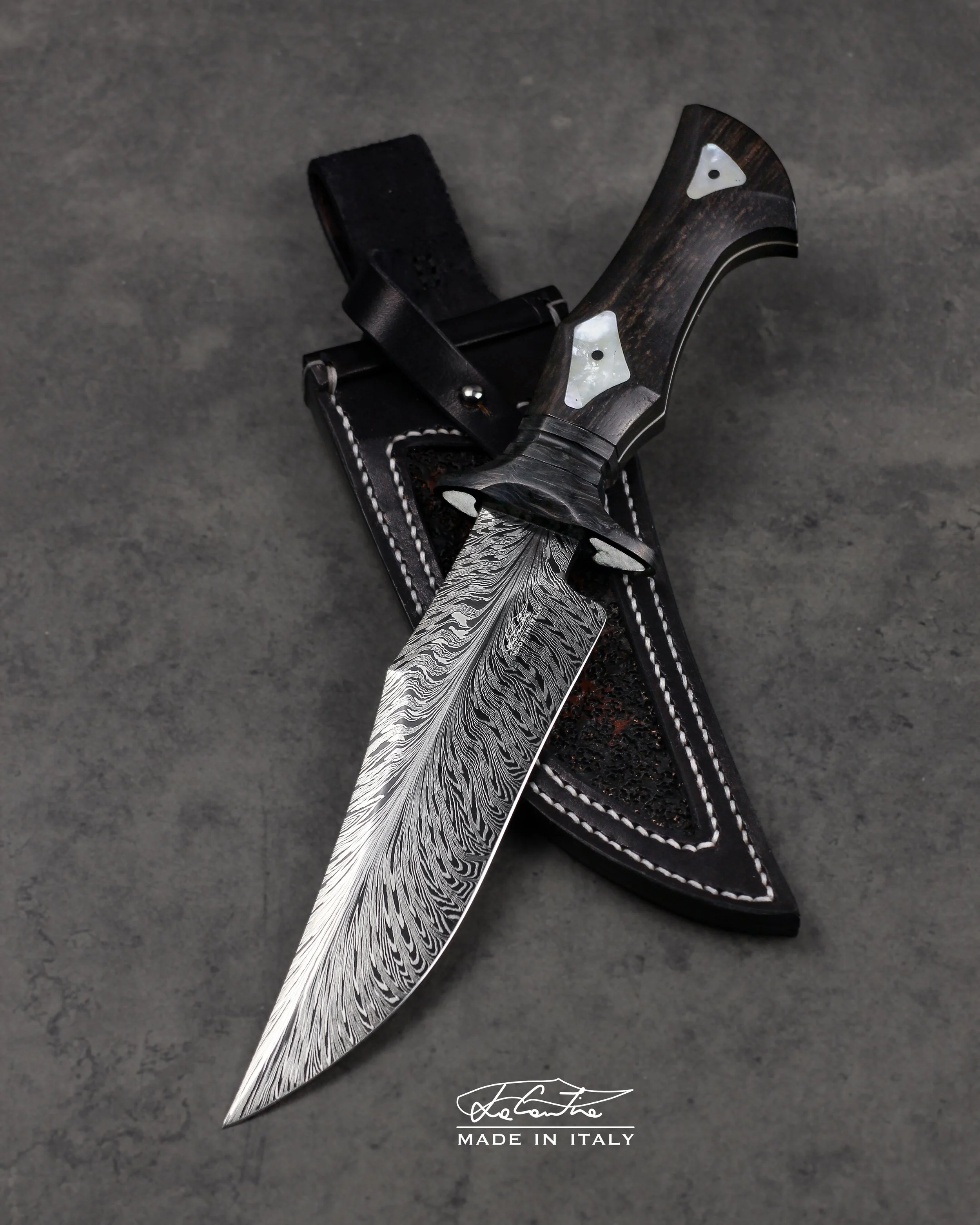 LAMA: Acciaio Damasco artigianale 1084-15n20, 59HRC. 
MANICO: Guardia e spaziatore in Carbonio, inserti di guardia e manico in Madreperla, Ebano, G10 bianco, pin in carbonio
FODERO: Pelle lavorata e cucita a mano.