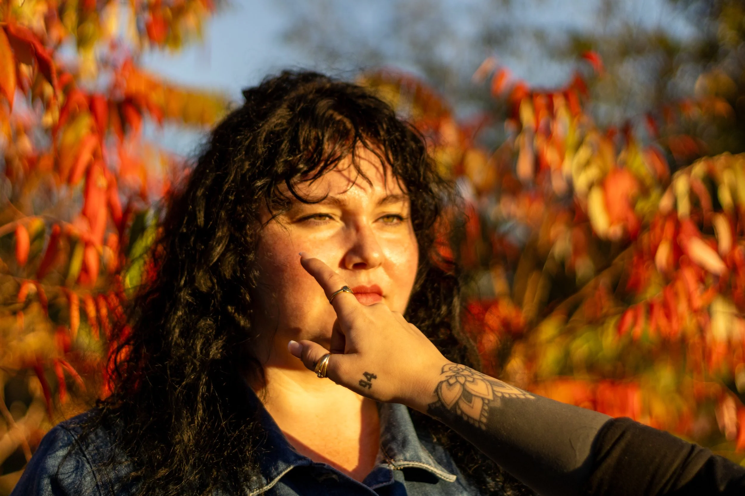 Dark haired woman standing in nature, a hand reaches for her