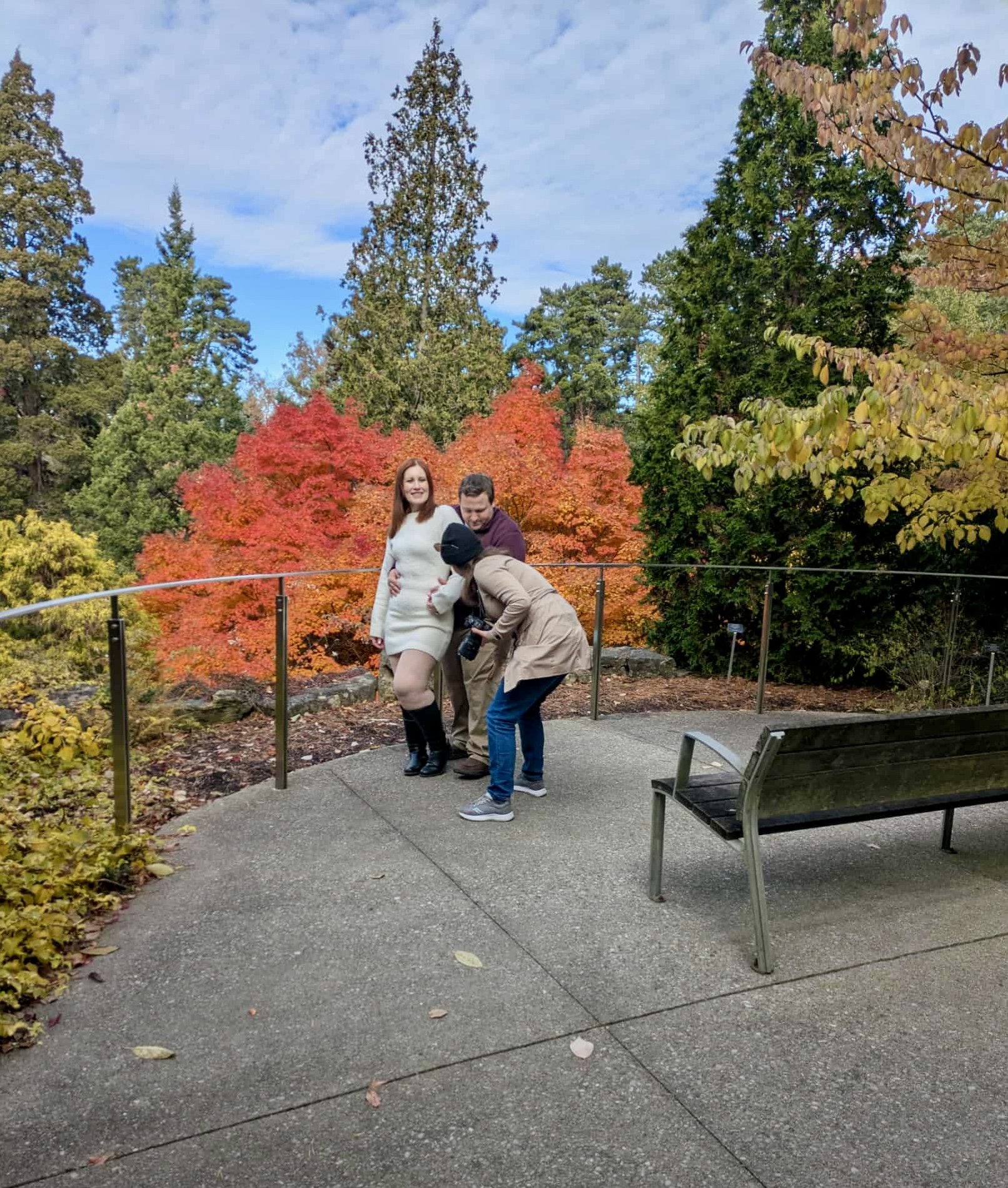 Photographer guiding a couple on how to pose, standing in a garden