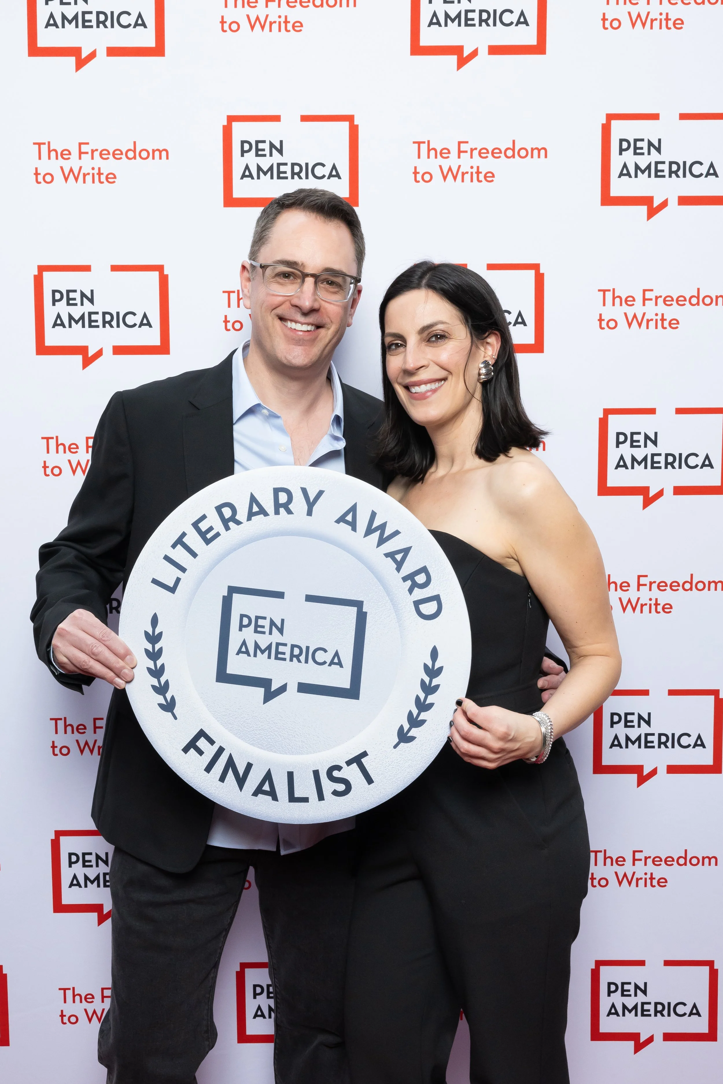 Author Christian Moody and his wife Margaret Kimball pose with a large PEN America Literary Awards sign at a PEN America event.