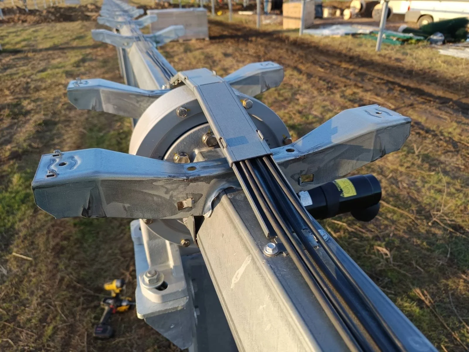 Close-up of a galvanized steel boat trailer with multiple support arms and a wheel at the center, on a grassy outdoor area.