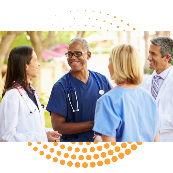 A diverse group of healthcare professionals, including doctors and nurses, are smiling and talking outdoors.