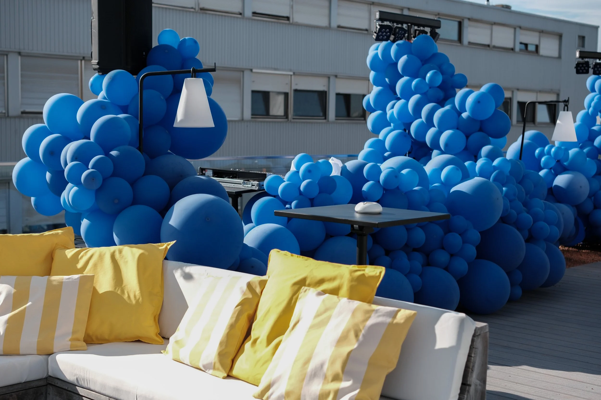 Eventlocation der Urban Spaces mit blauen Ballons und gelben Kissen auf einer Couch.