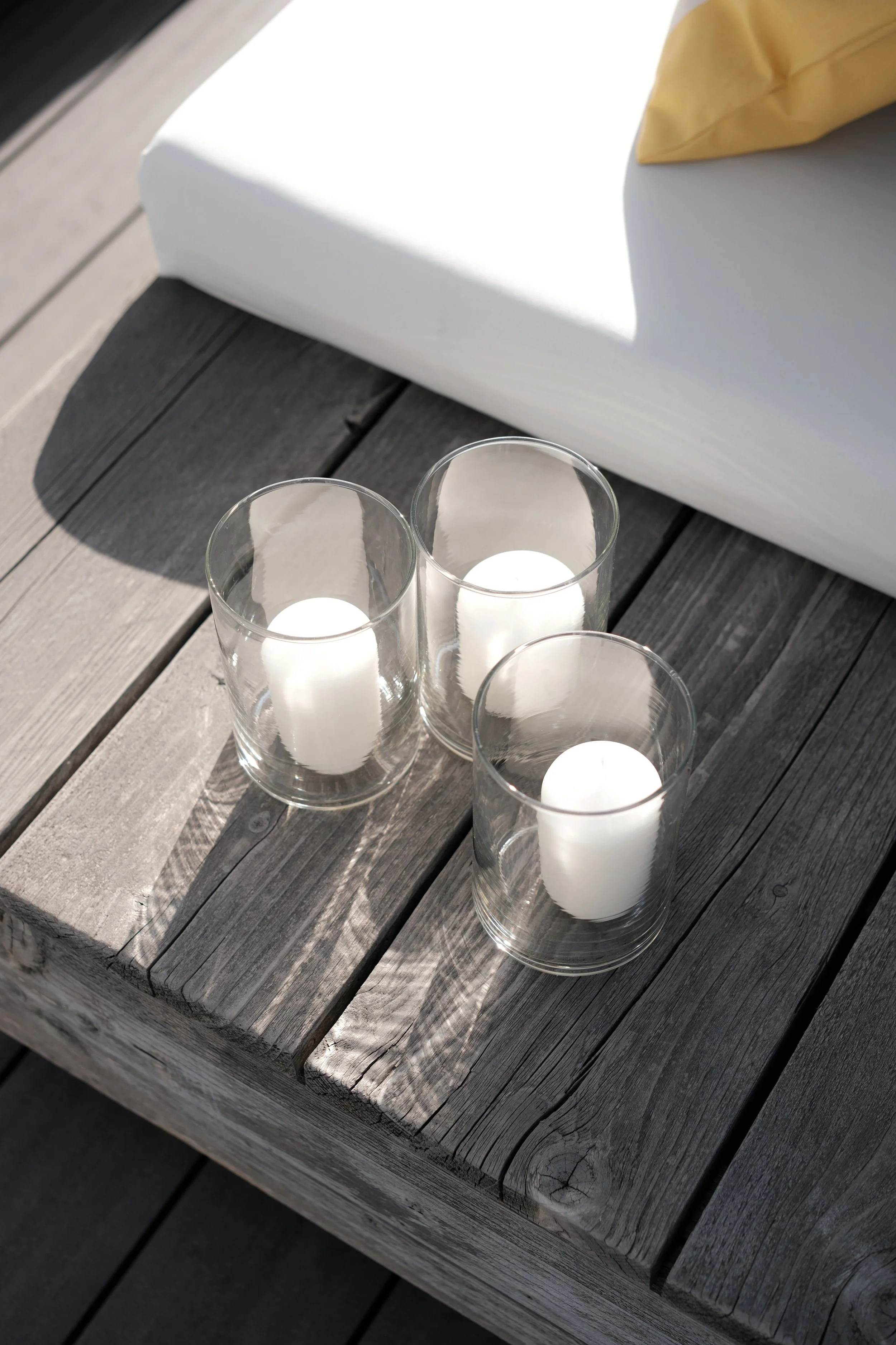 Drei Kerzen in Glasvasen auf einem Holztisch