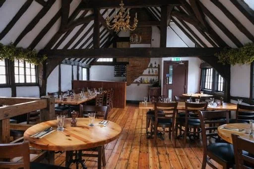 Interior of a cozy restaurant with wooden floors, tables, and chairs, and a chandelier hanging from the ceiling.