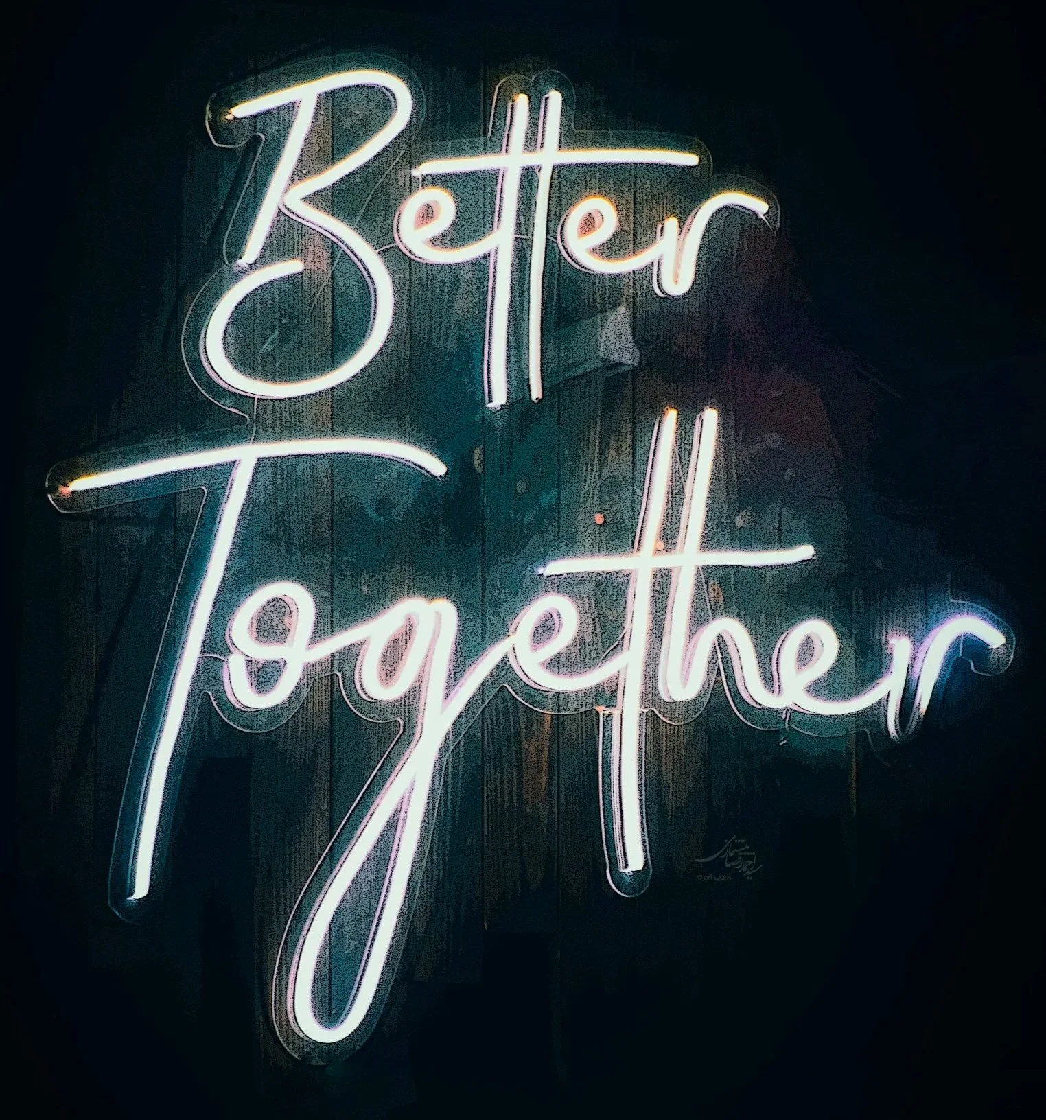 Neon sign with the phrase 'Better Together' in cursive letters, illuminated against a dark background.