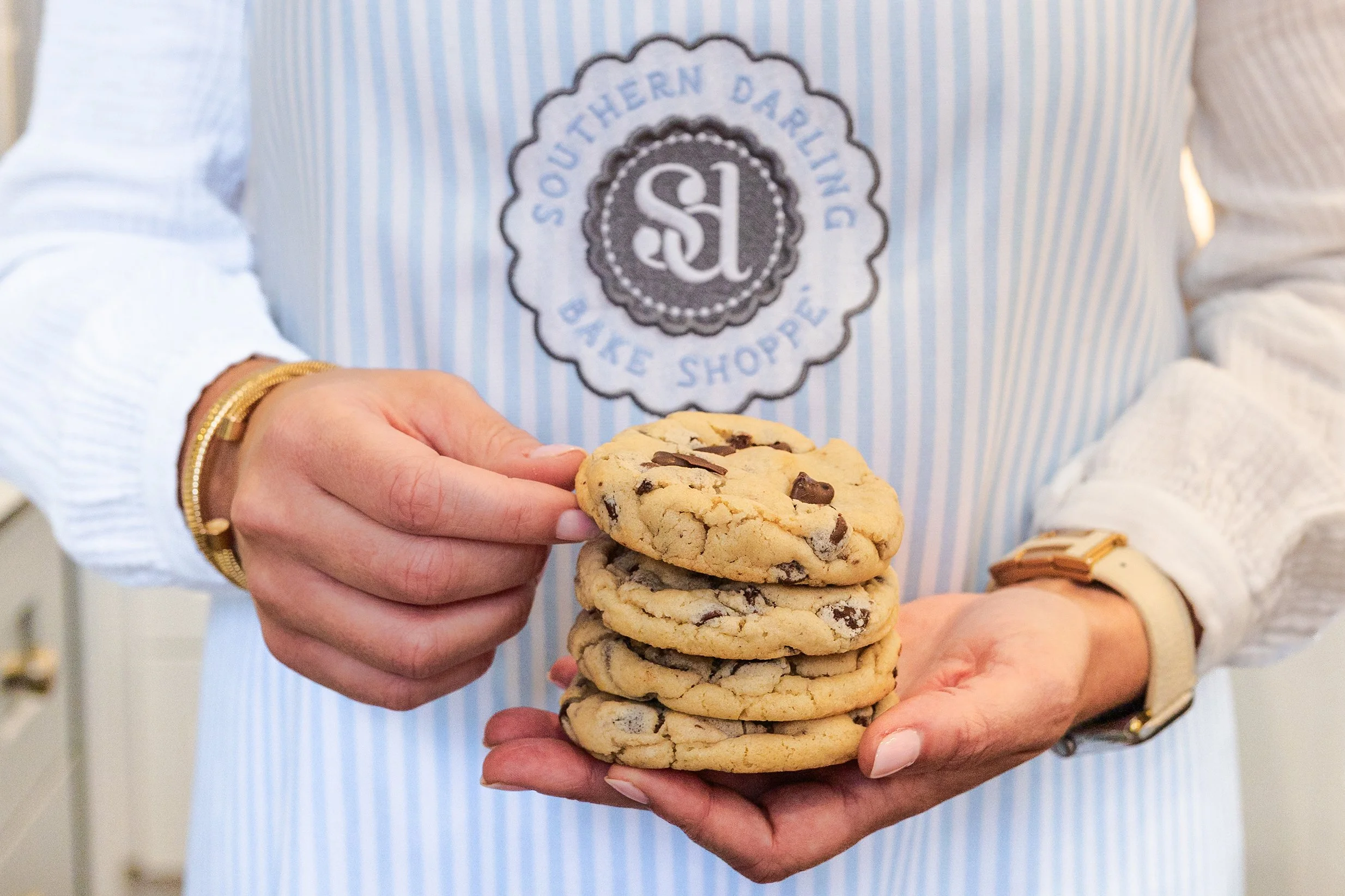 Baker at Southern Darling holding a stack of chocolate chip cookies.