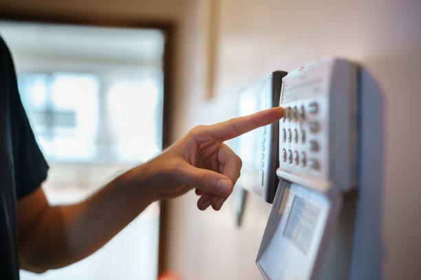 Person pressing a button on a security alarm control panel.