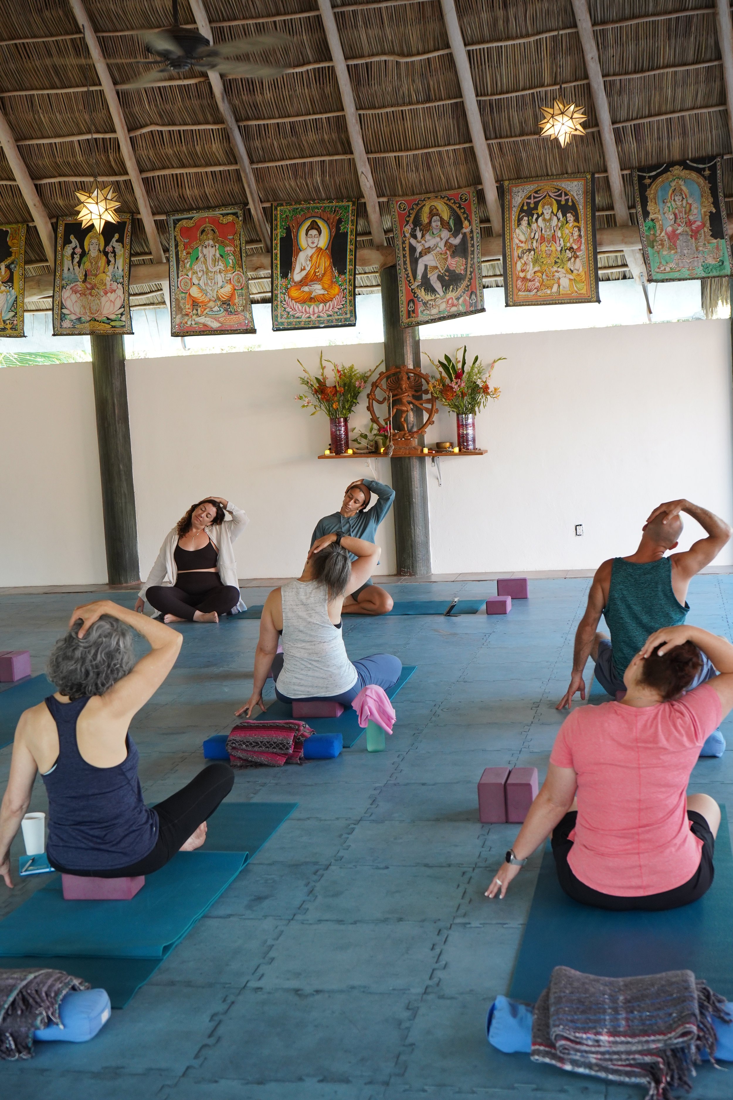 Guests practicing gentle seated yoga and neck stretches during a Sol Collective wellness retreat in Sayulita, Mexico
