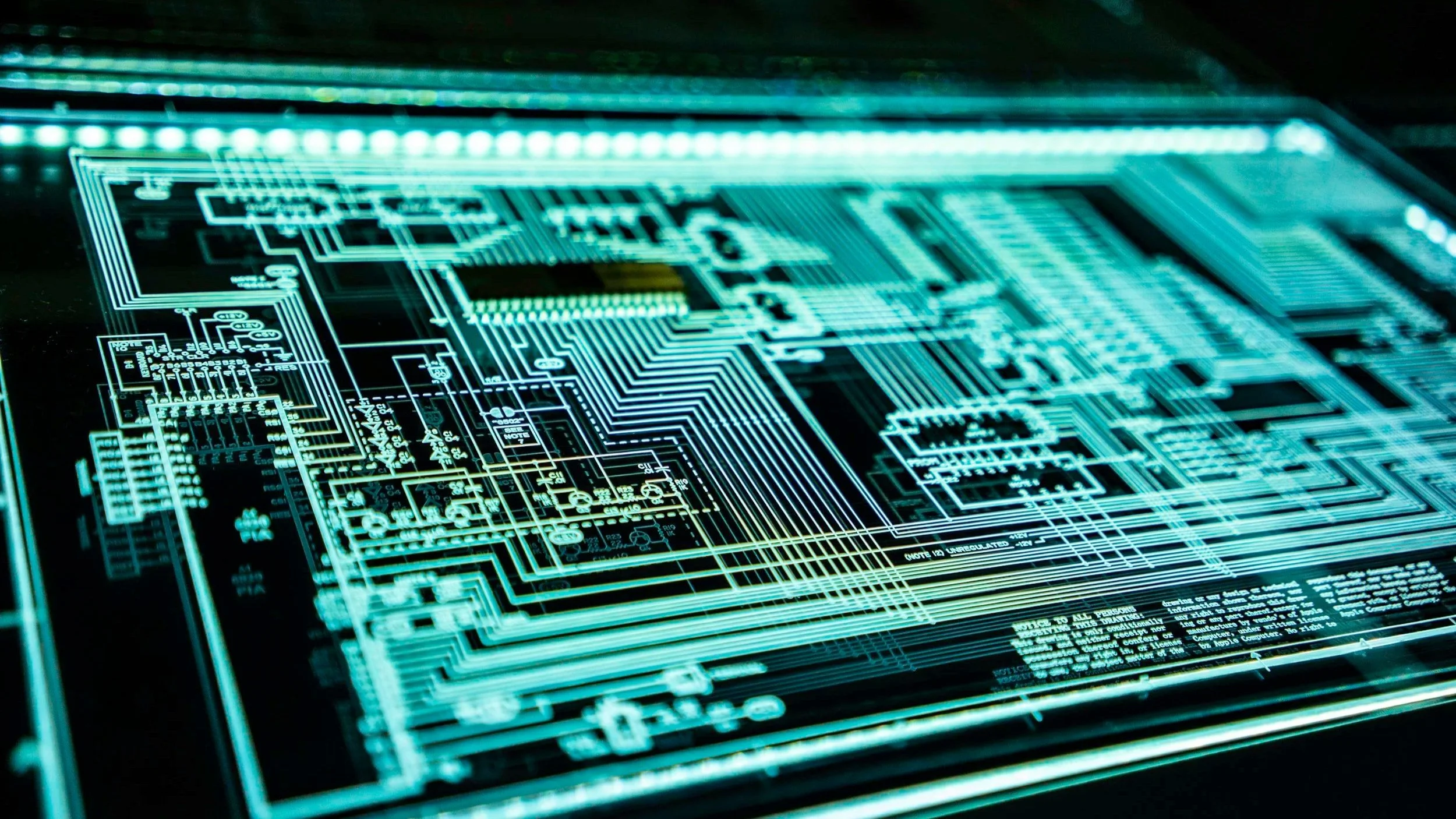 Schéma électronique sur un écran numérique affichant des circuits imprimés en points lumineux bleus et verts.