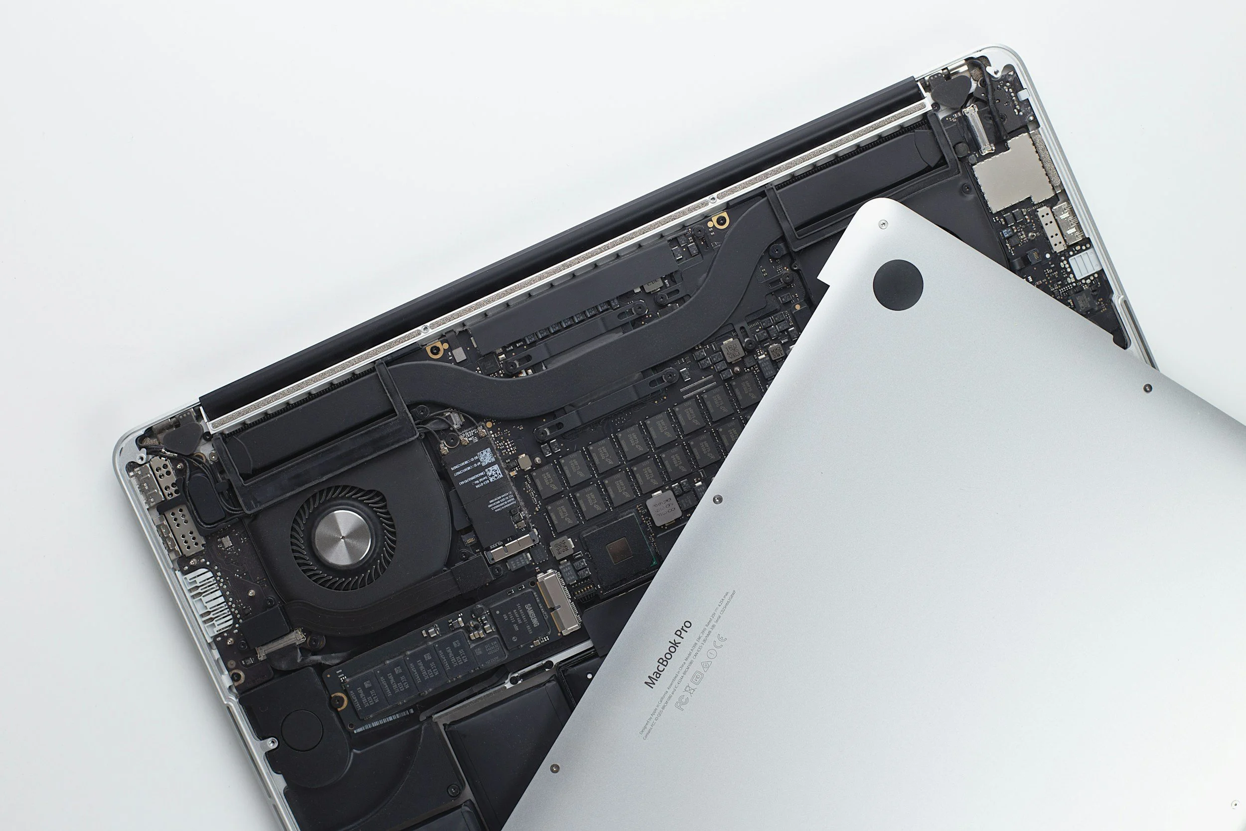 Intérieur d'un ordinateur portable MacBook Pro avec le capot arrière soulevé, montrant la carte mère et les composants électroniques.