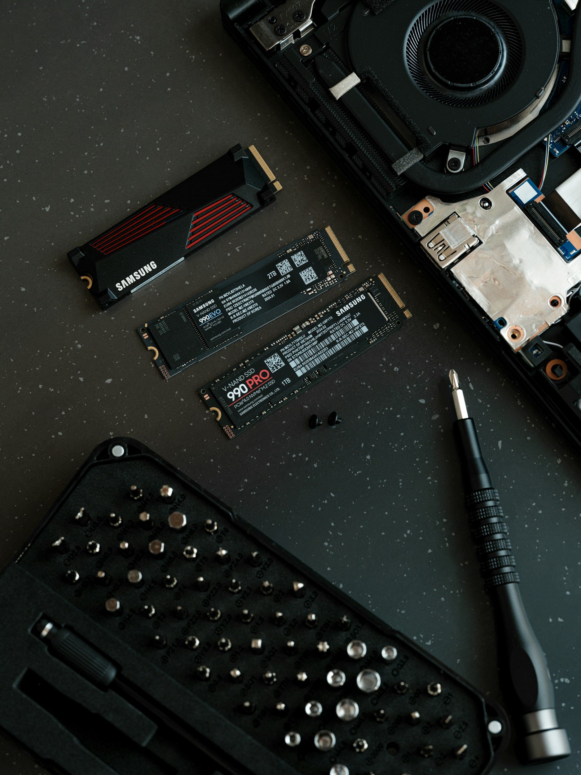 Composants informatiques, cartes SD, tournevis, et un tournevis prise dans une table de travail.