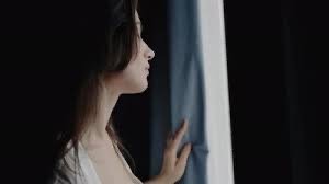 Woman sitting quietly by a window in soft winter light, reflecting at the end of the year while navigating grief and emotional healing.