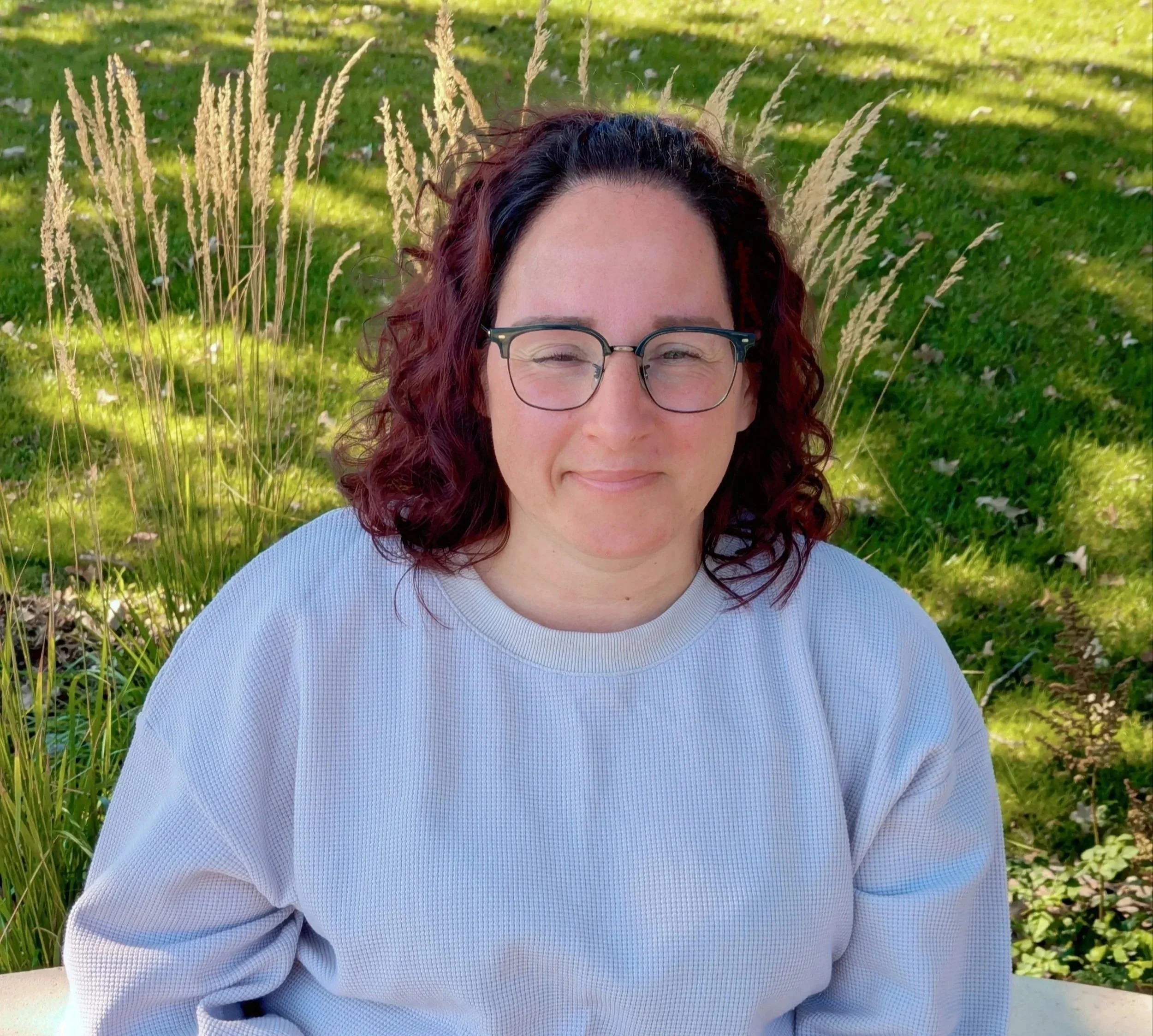Michelle: Brown curly hair, glasses, gray shirt. She appears warm and welcoming. 