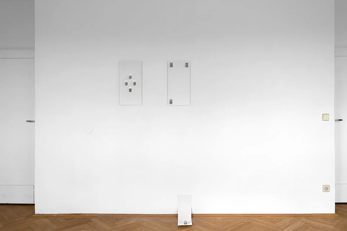 A plain white wall with electrical boxes and outlets, and a small white object on the floor in front of it.