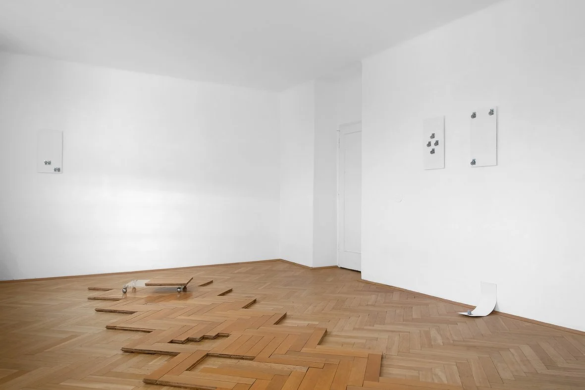 Empty room with white walls and unfinished wooden flooring, some wood planks are disassembled on the floor, and electrical panels are on the wall.