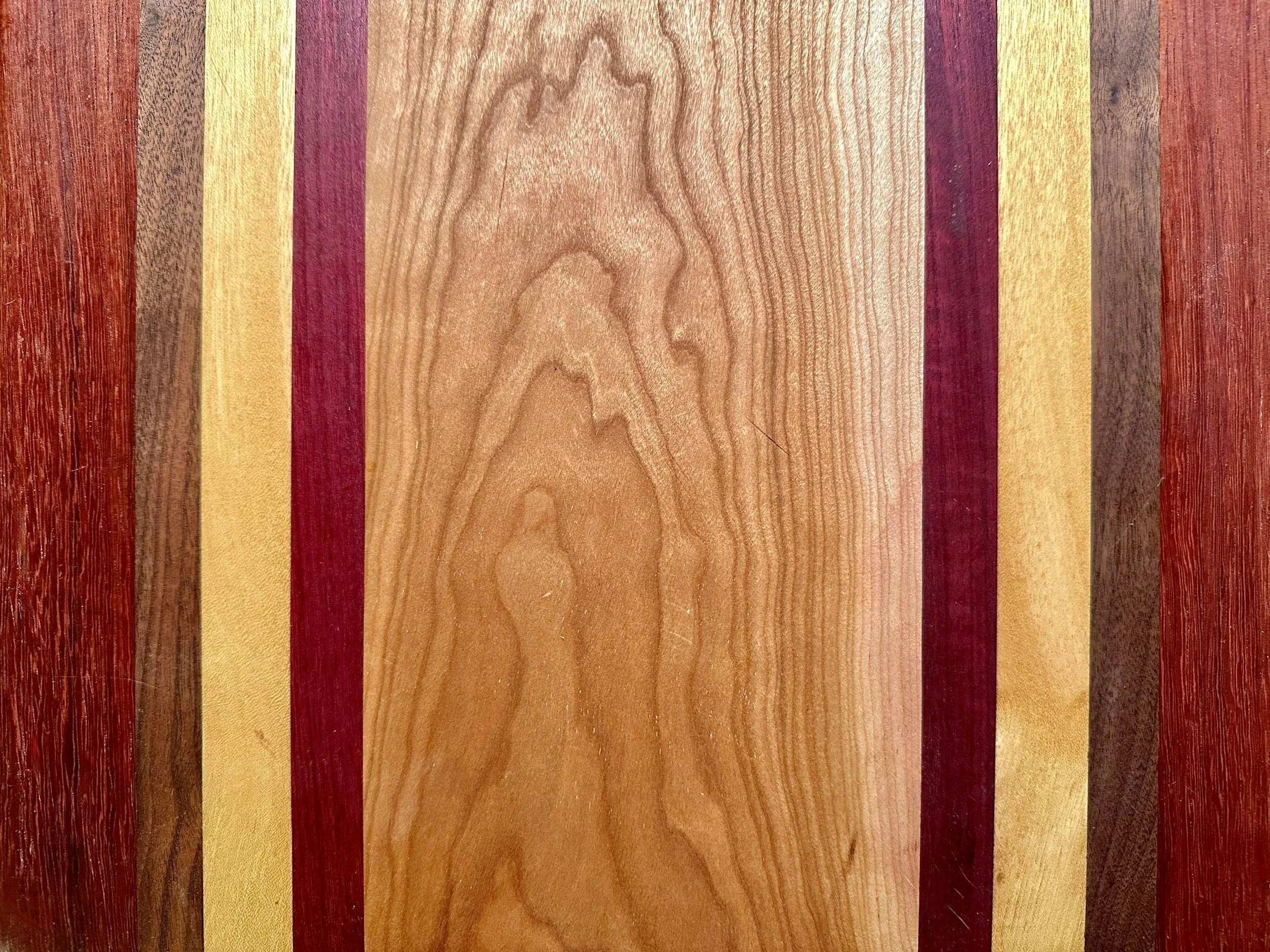 Wooden plank with striped pattern of various shades of brown, yellow, and red.